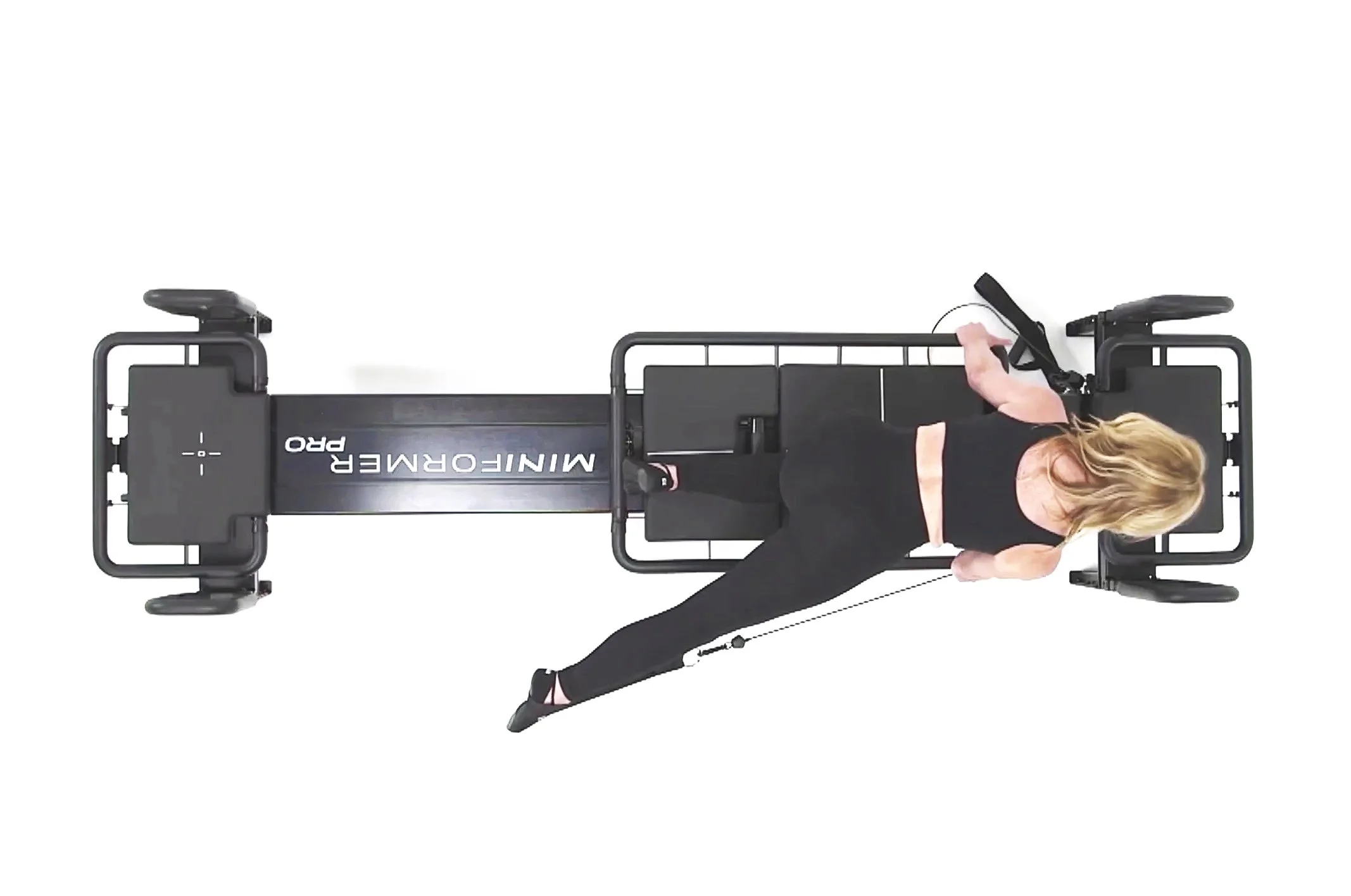 Woman performing an exercise on a Lagree Mini PRO fitness device, lying on her side with her arm supporting her head and legs moving against resistance.