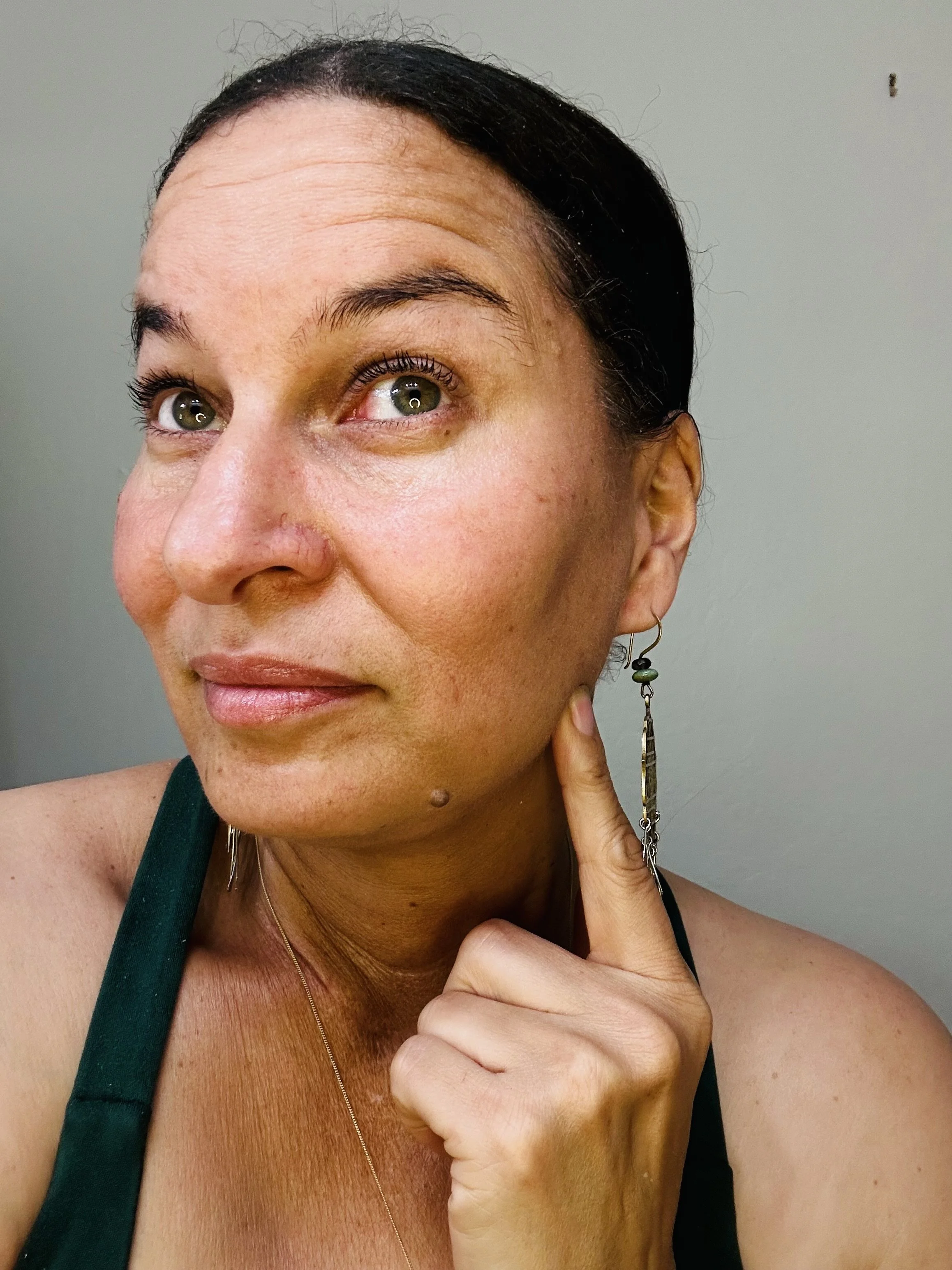 Close-up of woman pointing to jaw muscle area where tension builds, showing location for TMJ massage.