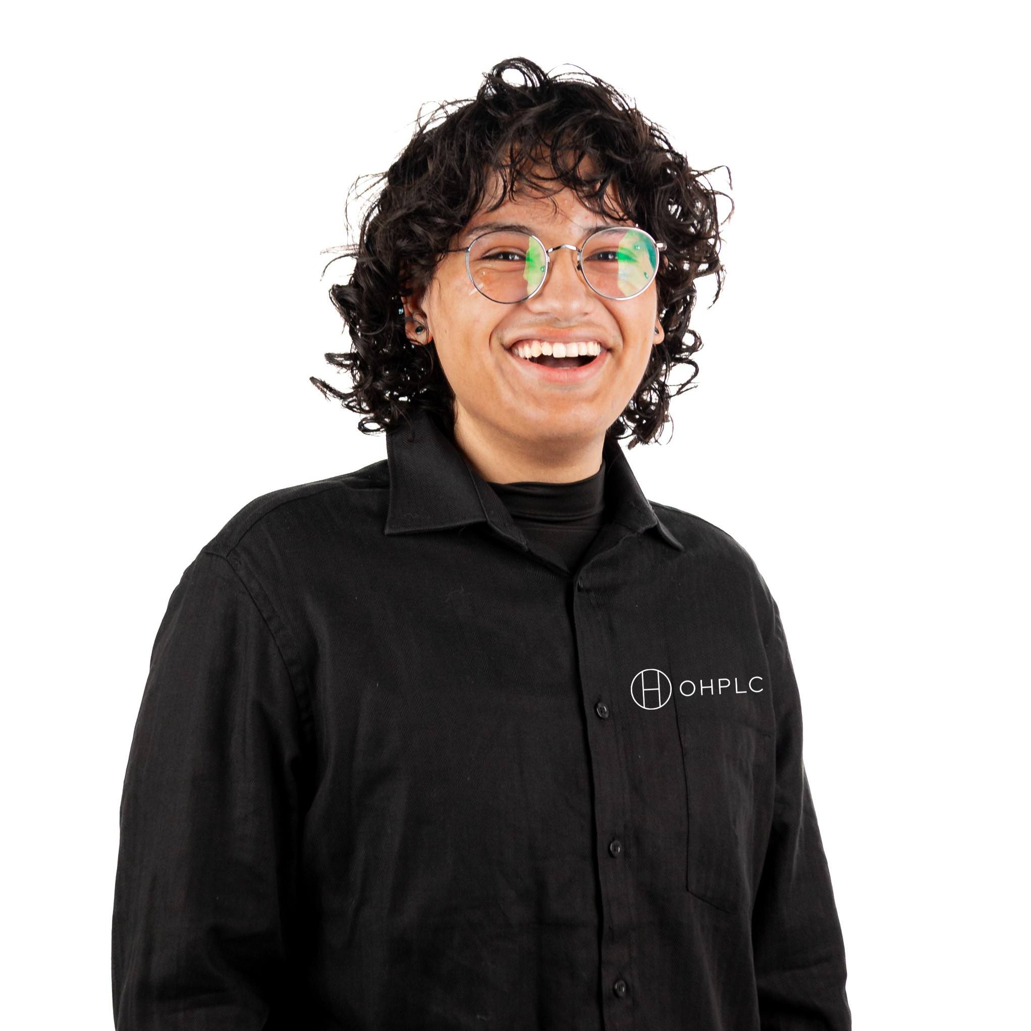 Smiling person with curly hair, wearing glasses and a black shirt with 'OHPLC' logo, standing against a white background.