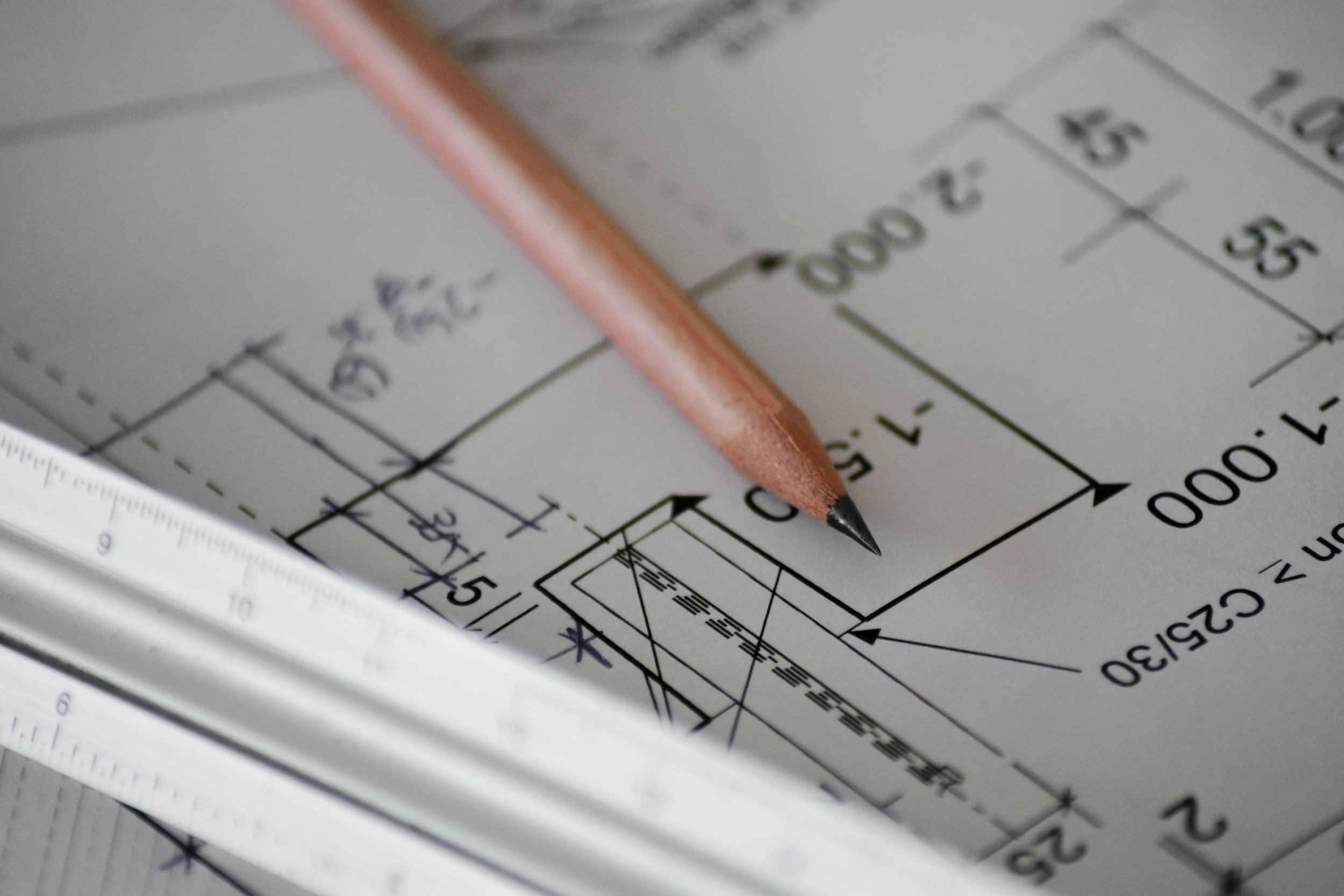 Architectural blueprint with a wooden pencil, a measuring ruler, and a calculator.