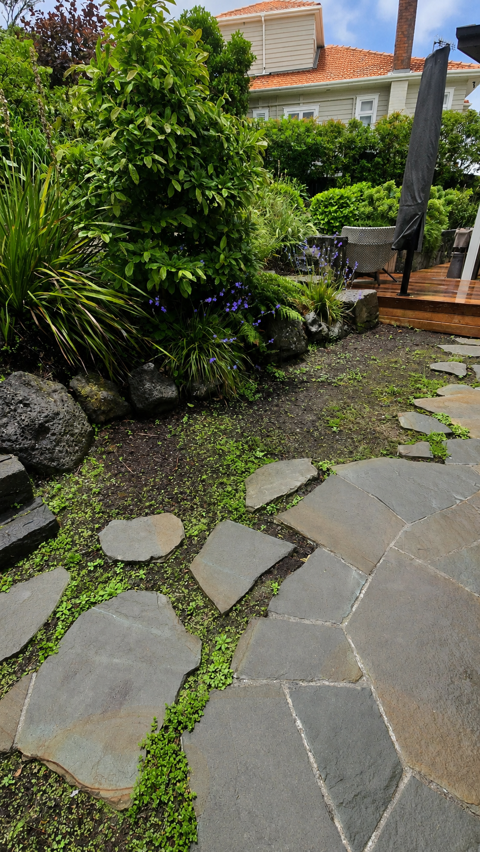 Irregular natural stone garden pathway with organic stepping stones, groundcover planting and layered garden landscaping.