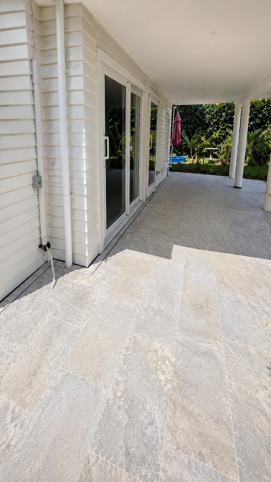 Contemporary outdoor porcelain paving installed beneath a covered patio, creating a seamless transition between indoor and outdoor living spaces.