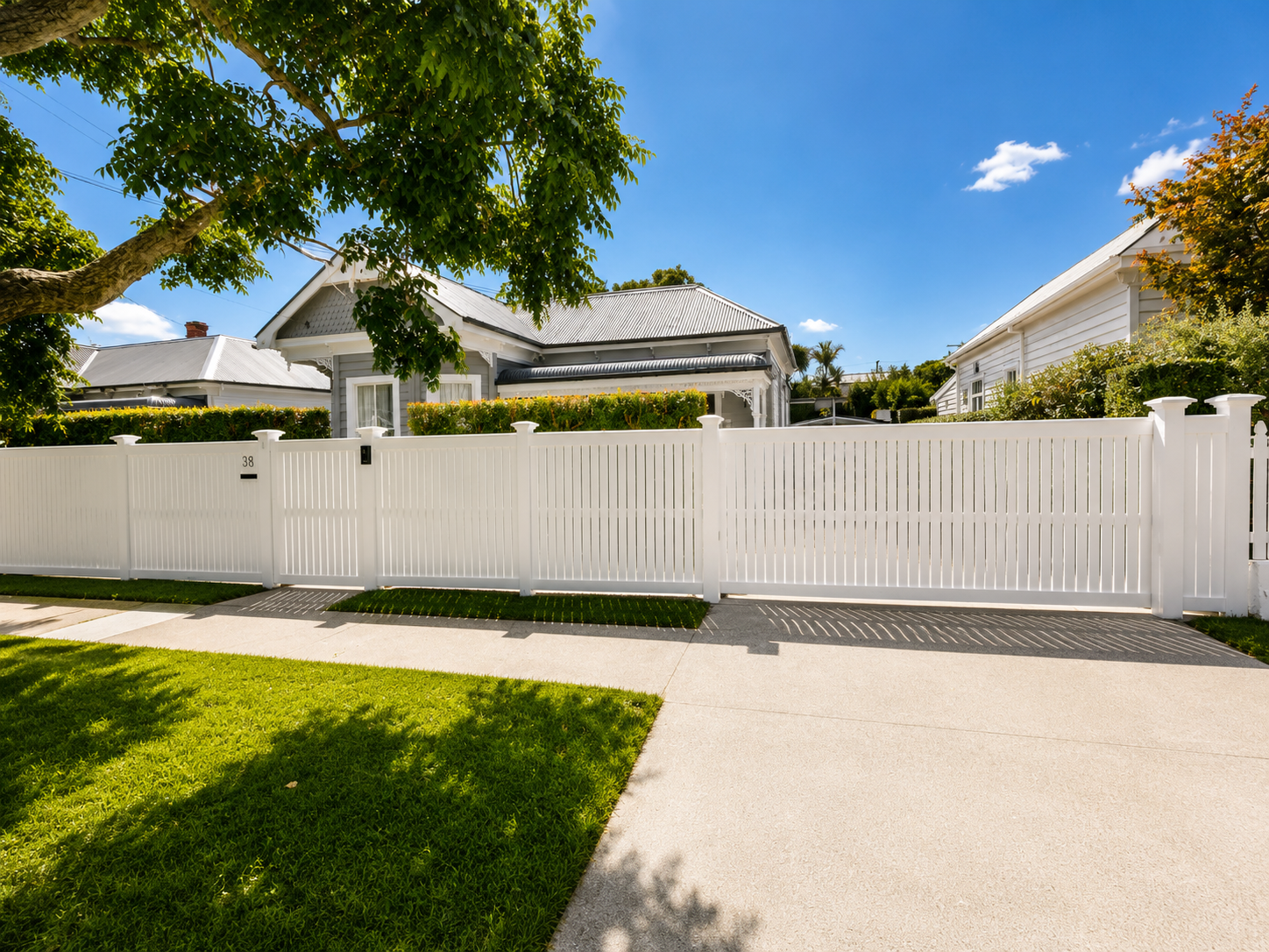 Modern white aluminium picket fence with matching pedestrian gate, landscaped frontage, and heritage villa in Auckland, installed by Whenua Scapes.