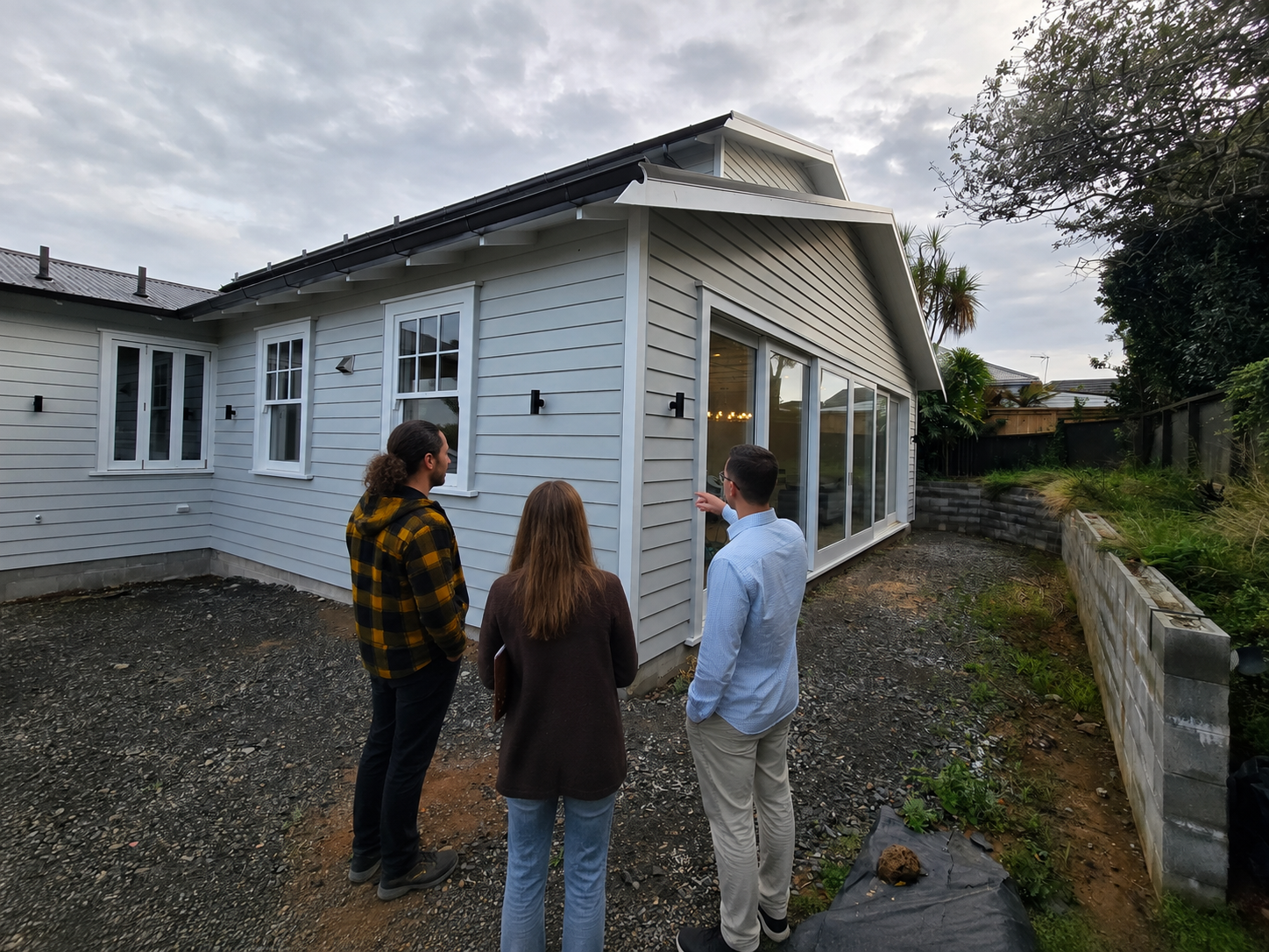 Professional landscape design consultation at a new home in Auckland, with a landscape designer discussing the outdoor project with homeowners while reviewing the garden and exterior spaces.