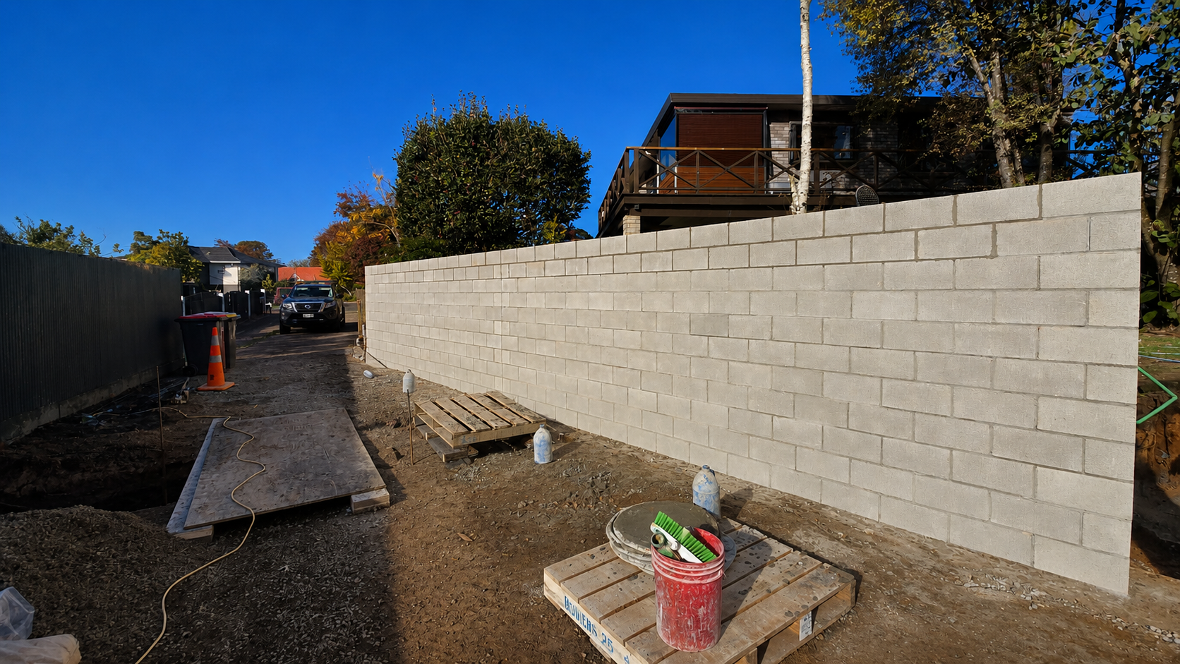 New concrete block retaining wall under construction for a residential landscaping project in Auckland, New Zealand, showing reinforced masonry and structural blockwork.
