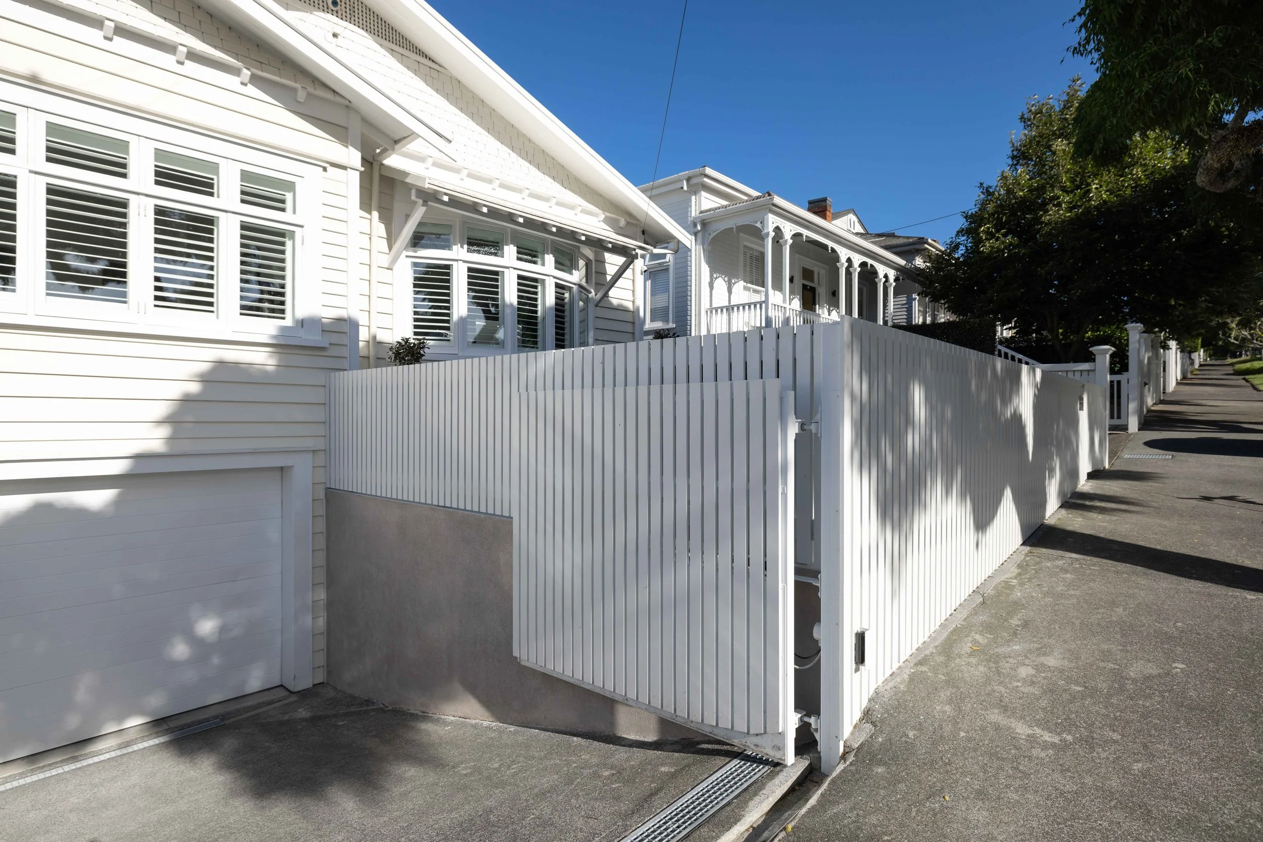 Rendered concrete retaining wall supporting a residential boundary with custom fencing as part of a retaining wall construction project in Auckland, New Zealand.