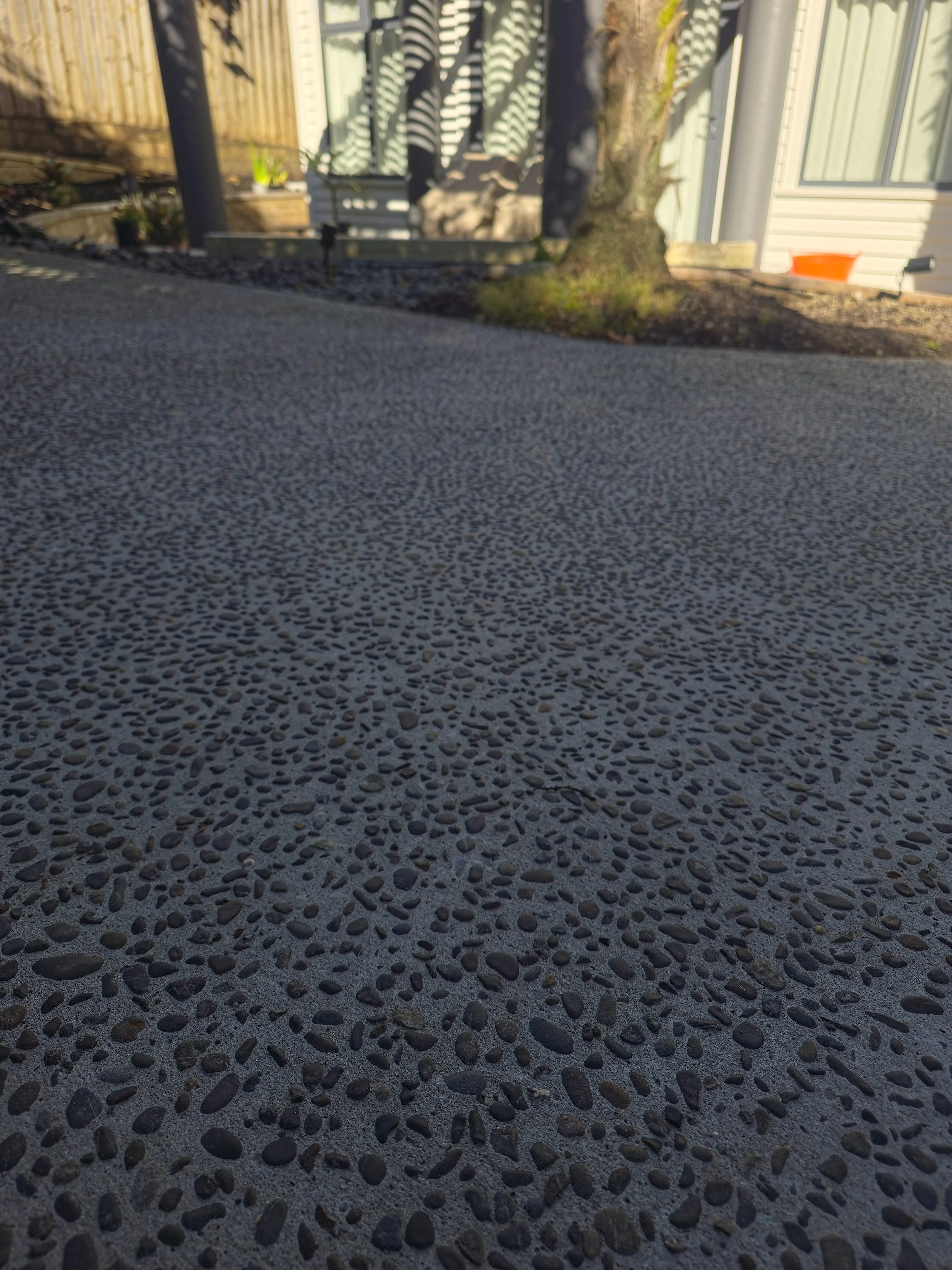 Close-up of exposed aggregate concrete showcasing the natural stone texture and durable finish used in residential landscape construction.