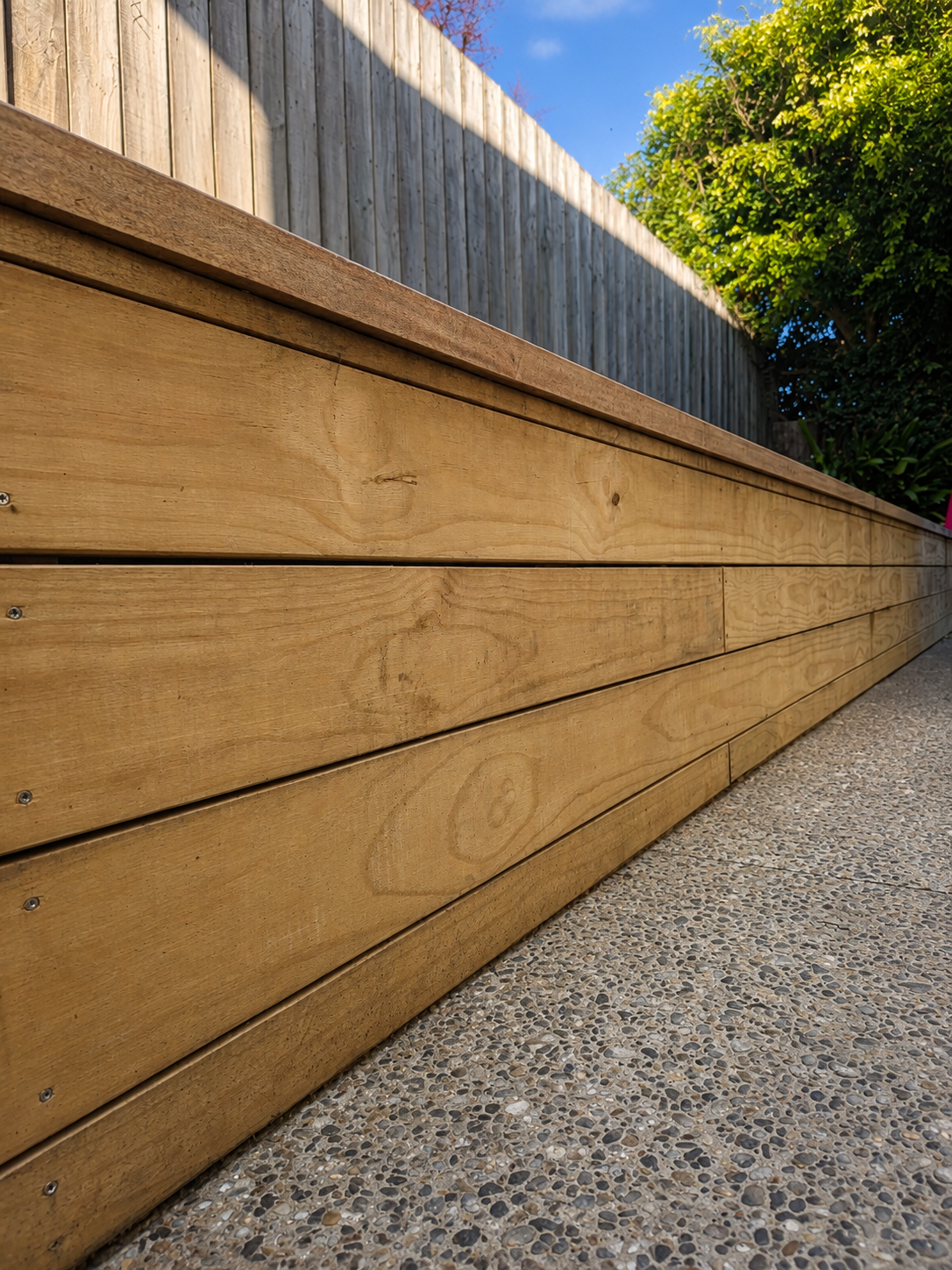 Timber retaining wall constructed with hardwood retaining boards for a residential landscaping project in Auckland, New Zealand.
