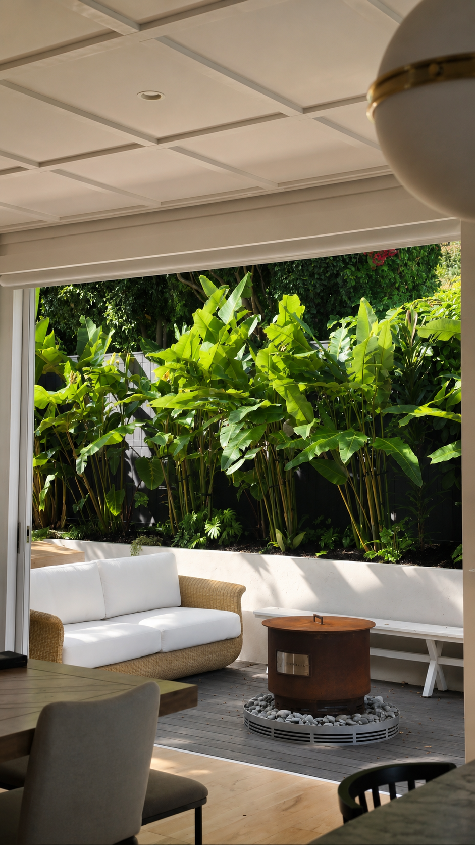 Tropical privacy screening with layered planting, timber fencing, and outdoor living space designed to create a private backyard retreat in Auckland.