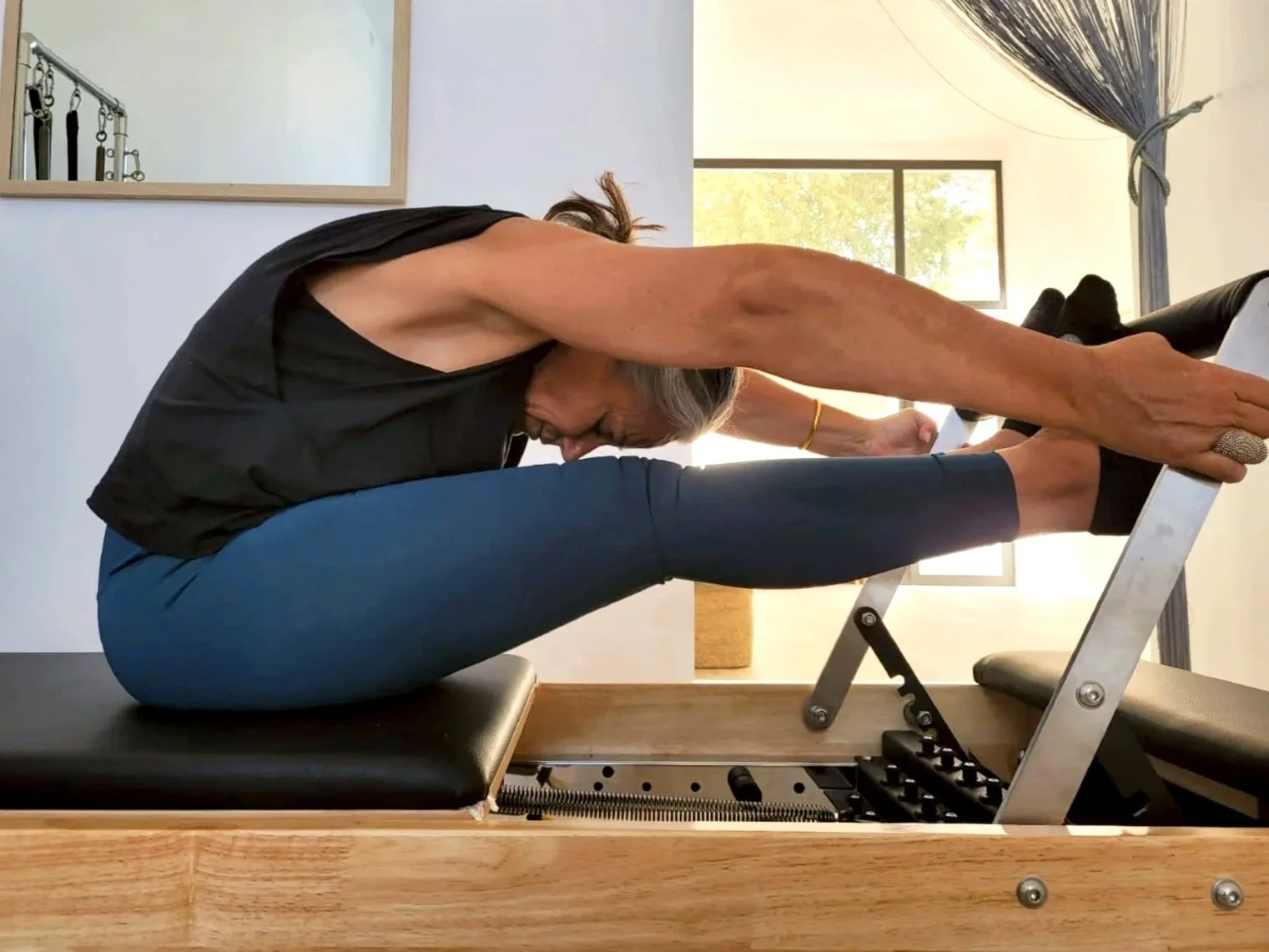 Alumna de Alma Studio Palmanova haciendo pilates con máquina reformer.