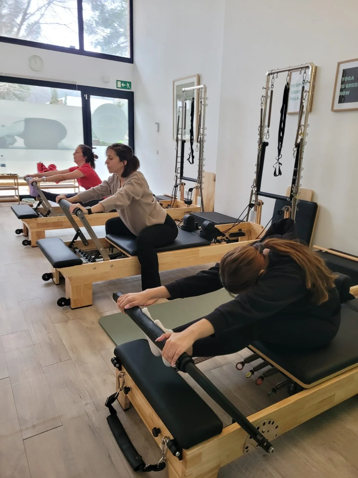 Tres futuras mamás haciendo pilates con máquina reformer en Alma Studio Palmanova.