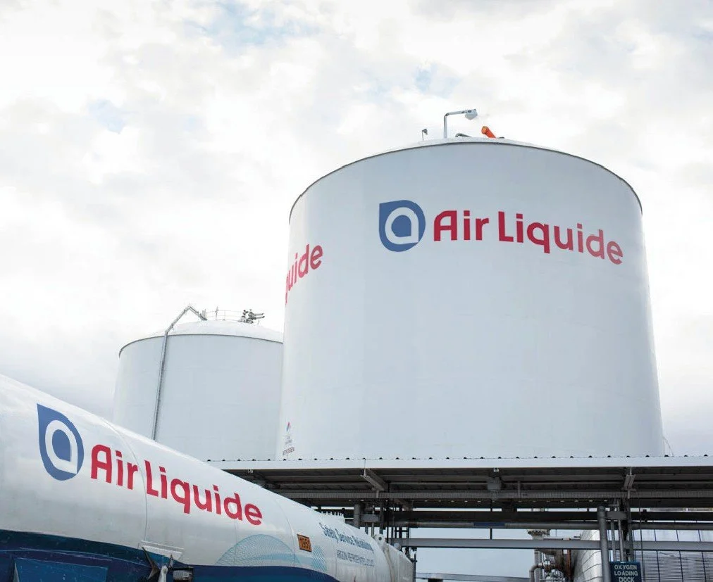 Réservoirs industriels et camion-citerne arborant le logo Air Liquide dans une installation de production de gaz.