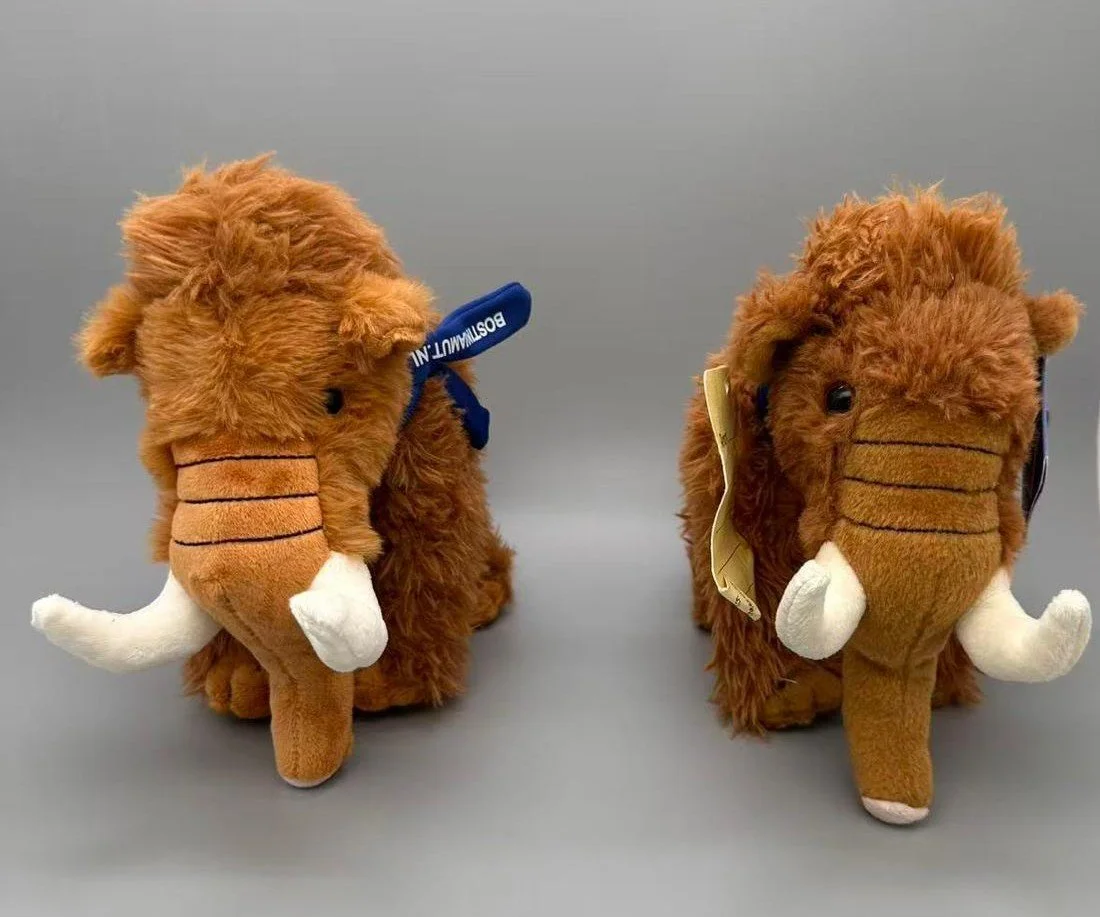 Deux peluches de mammouth brun roux avec de grandes défenses blanches, photographiées sur fond gris.