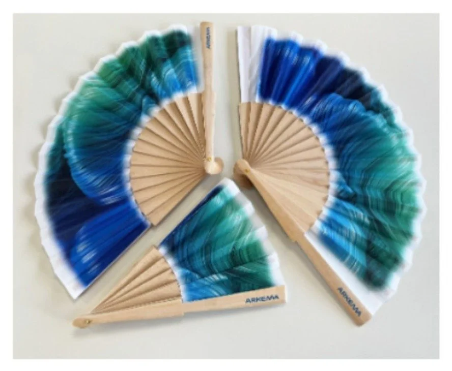 Trois éventails pliants en bois, aux motifs dégradés bleu et vert, disposés sur fond blanc.