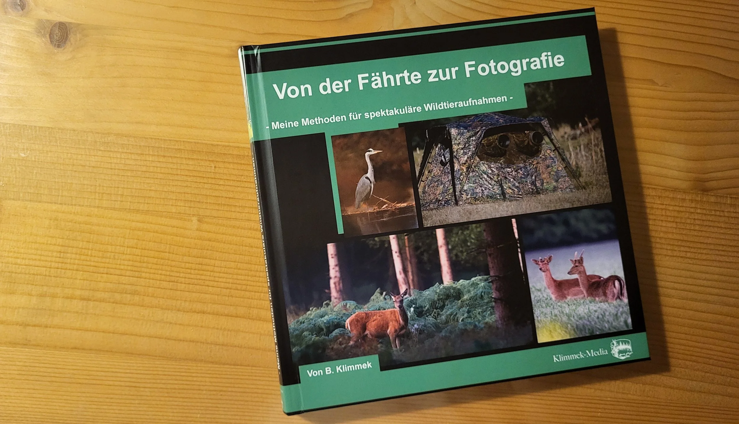Buch mit Titel 'Von der Fährte zur Fotografie' liegt auf einem Holztisch