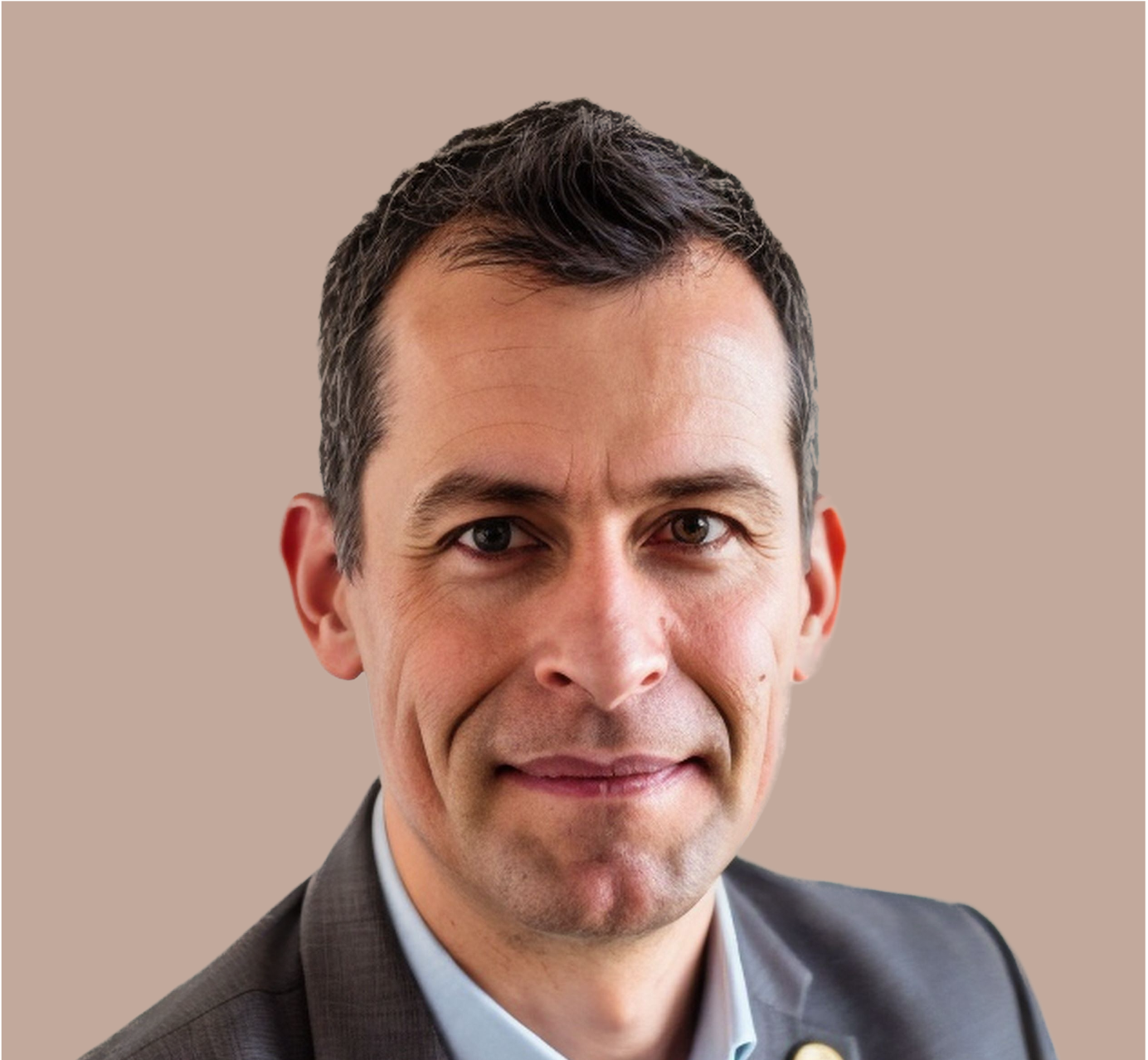 Porträt eines lachenden Mannes in einem Anzug vor beigem Hintergrund.