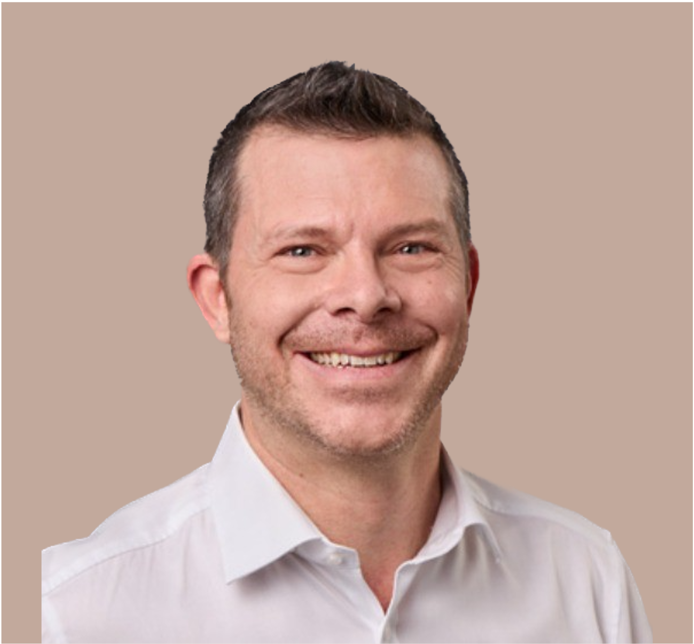Lächelnder Mann mit weißen Hemd, kurze braune Haare, hellbeige Hintergrund.