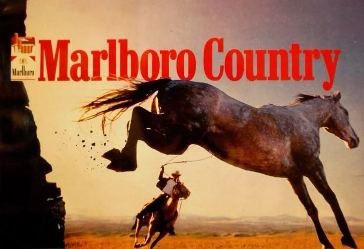 A horse rearing up and kicking a cowboy with a lasso on a grassy plain during sunset, with 'Marlboro Country' and Marlboro logo in the top left corner.