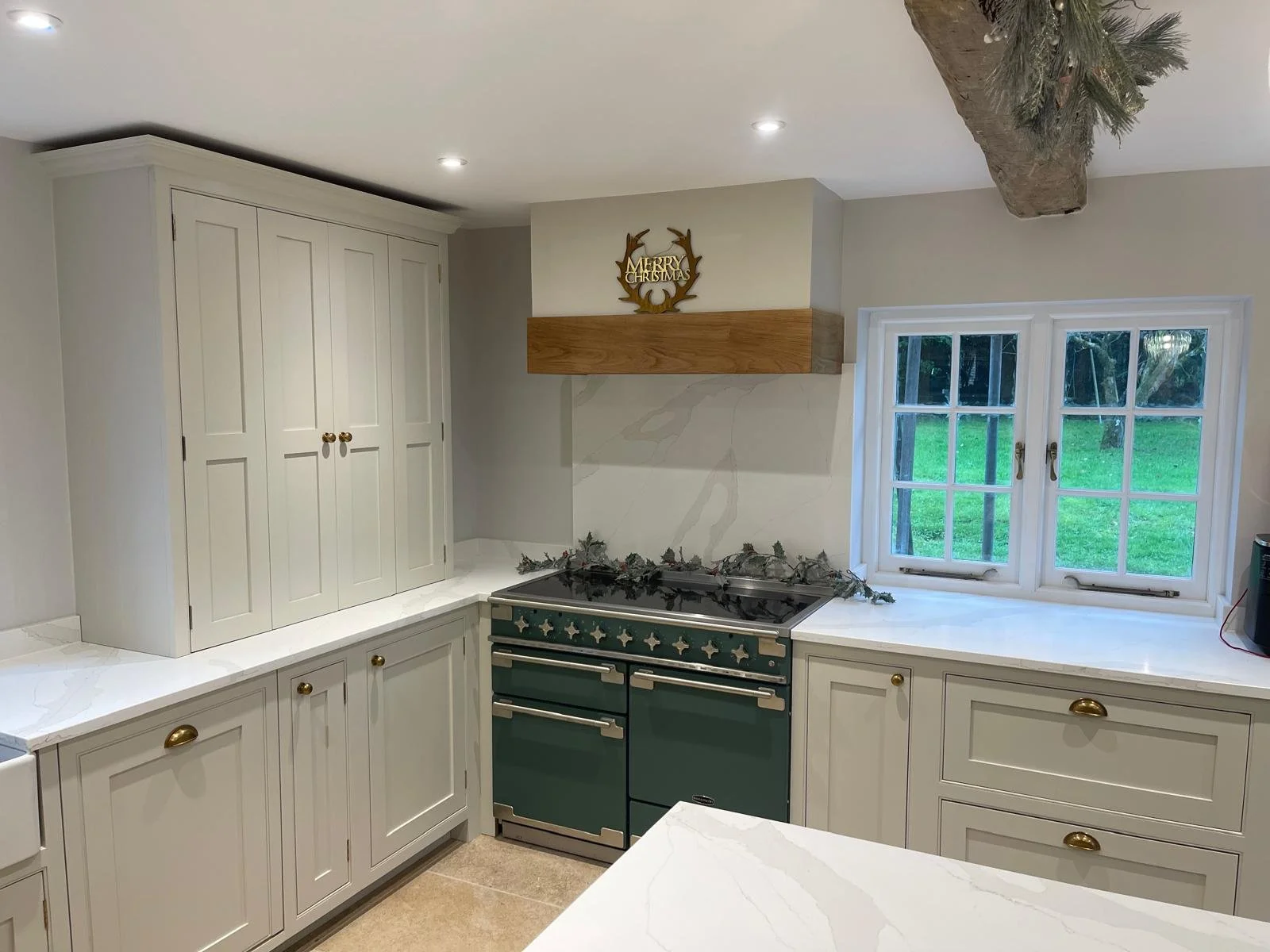 A kitchen with white cabinets, a green stove, work completed by NV Kitchens & Interiors.