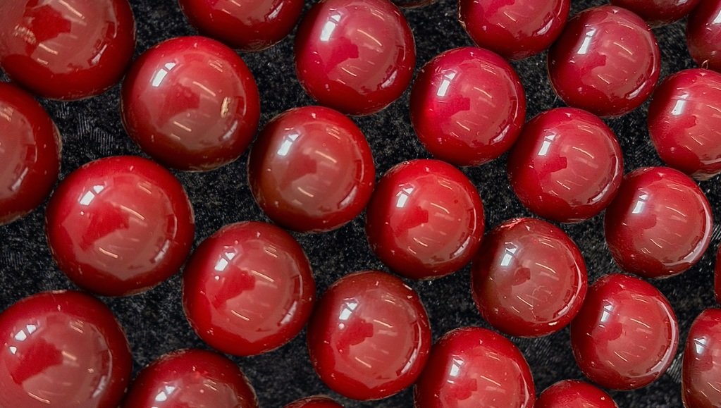 Close-up of shiny, red, spherical candies on a dark surface.