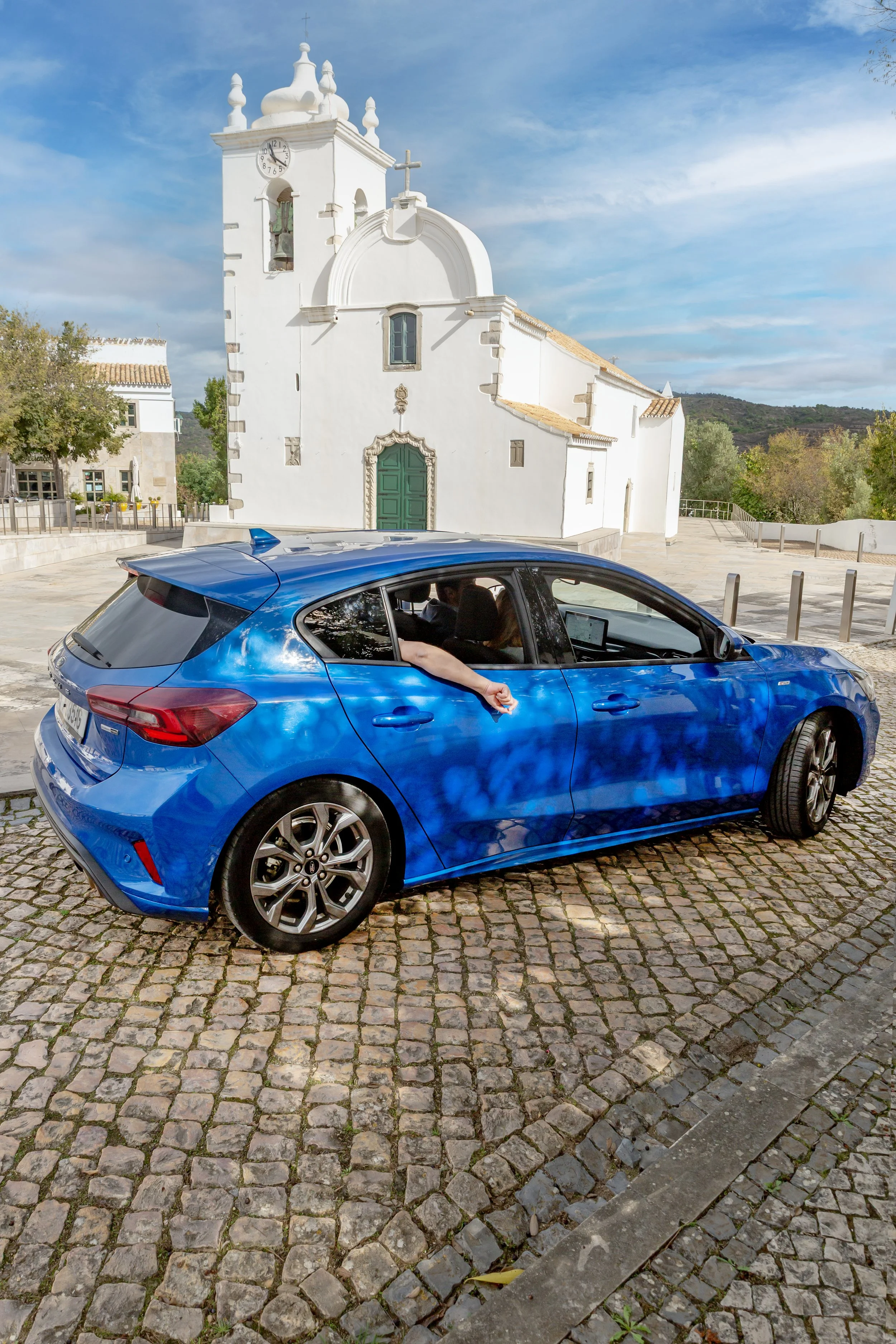 Blue car passing by Querença church in the Algarve inland