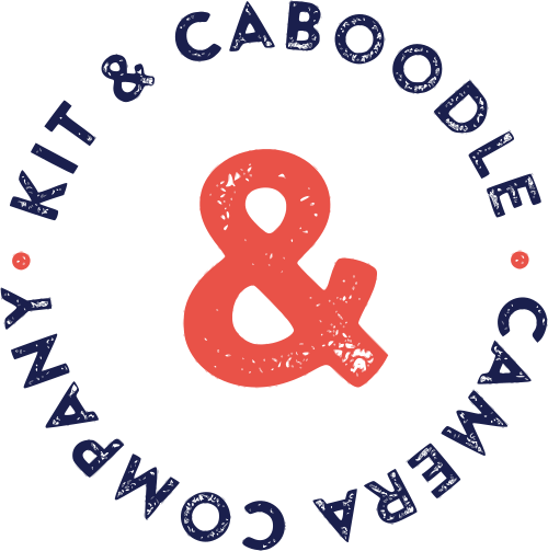 Logo for Kit & Caboole Cameroon, featuring the company name in a circular arrangement around a large ampersand symbol, with small red dots on either side.