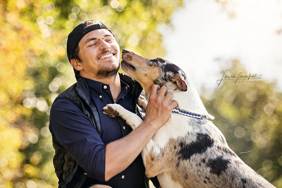 Uomo felice che tiene in braccio un Collie Smooth, entrambi sorridenti all'aperto con sfondo di alberi autunnali.
