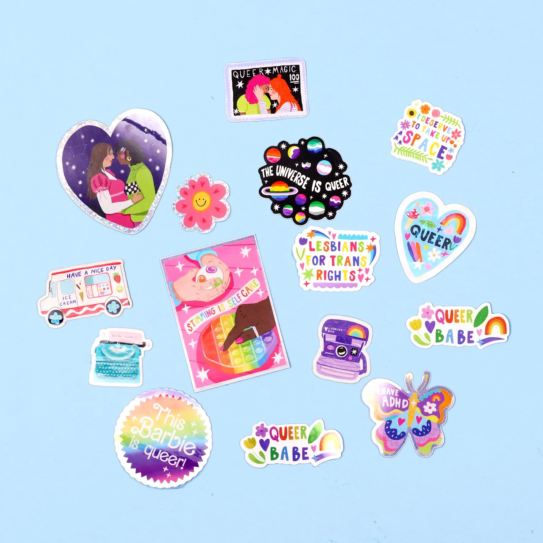 A collection of colorful stickers on a light blue background. The stickers feature messages and images promoting LGBTQ+ pride and inclusivity, such as 'QUEER MAGIC,' 'THE UNIVERSE IS QUEER,' 'LESBIANS FOR TRANS RIGHTS,' 'QUEER BABE,' 'I DESERVE TO TAKE UP SPACE,' and illustrations of rainbow and LGBTQ+ symbols.
