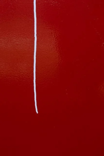 Close-up of a red surface with a vertical white line in the middle.