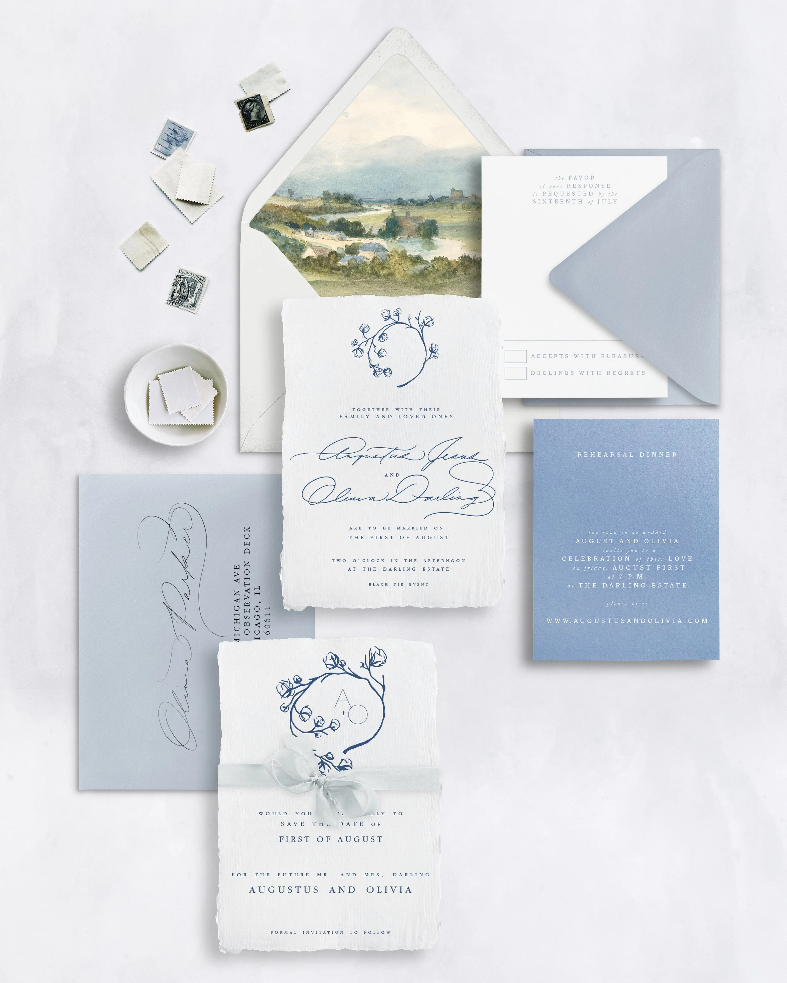 Invitation and wedding stationery set with blue and white designs, envelopes, stamps, and a save-the-date card for August 1st wedding of Augustus and Olivia.