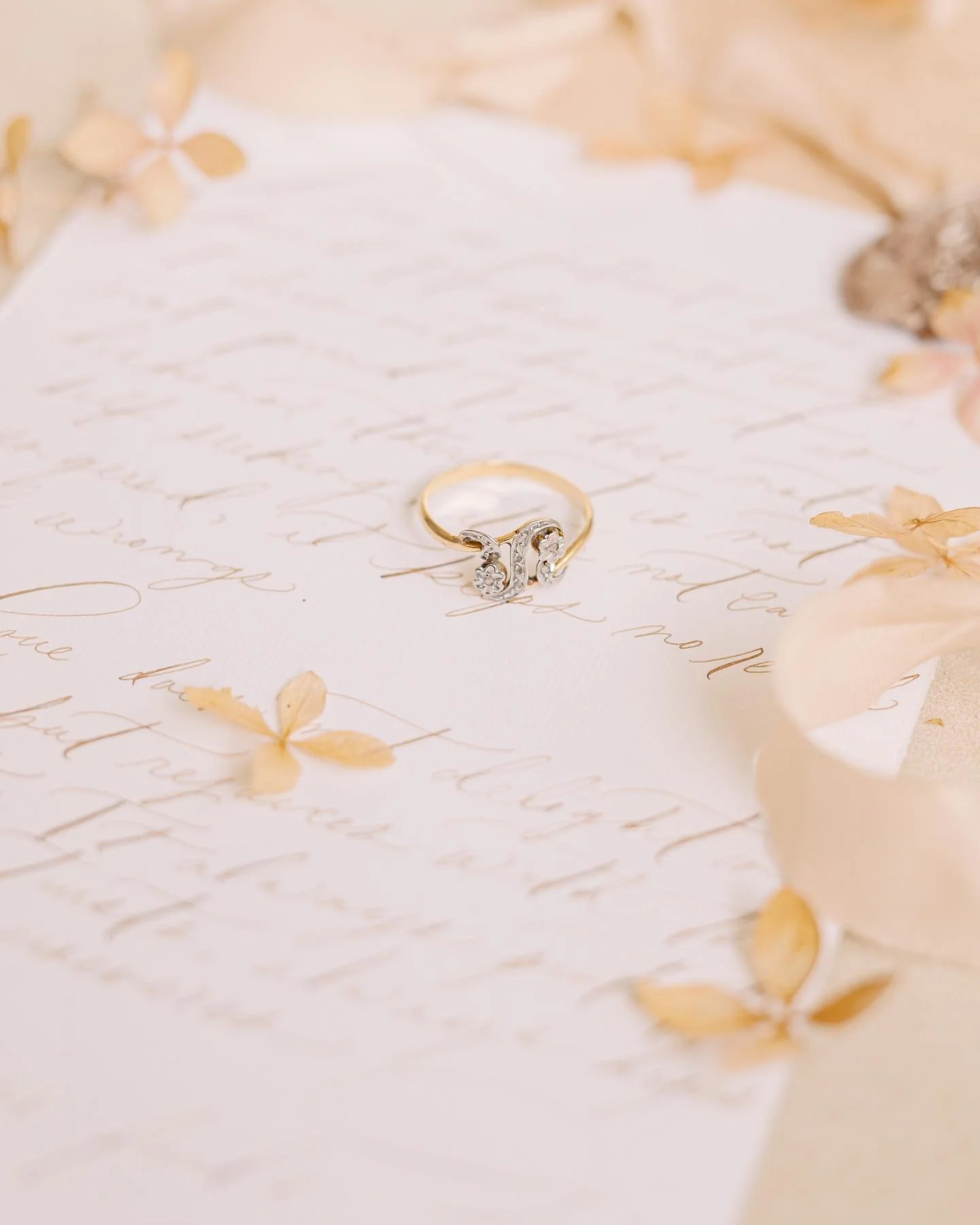 A wedding ring placed on handwritten love letter surrounded by dried flowers.