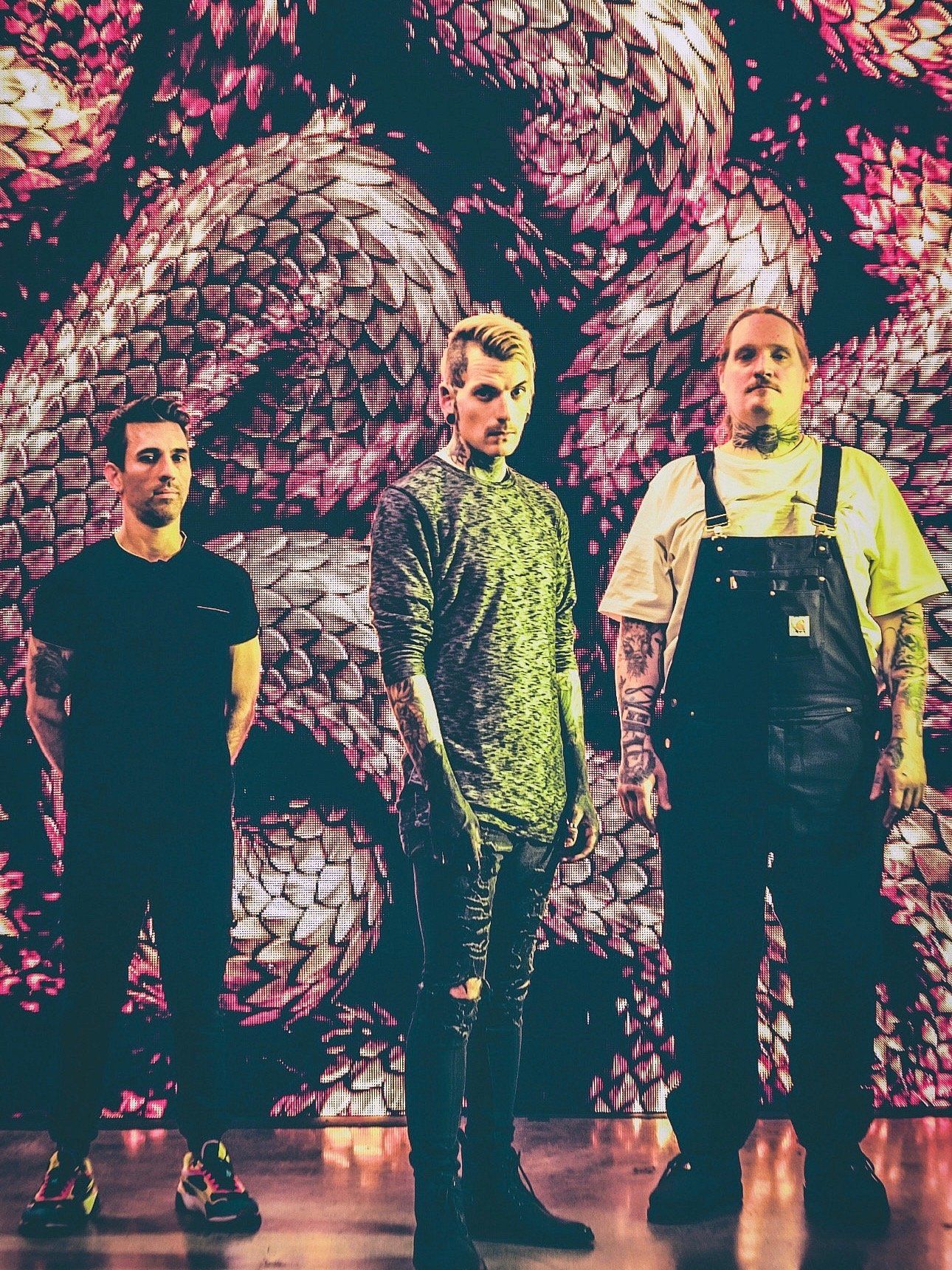 Three men standing in front of a digital screen with a floral or abstract pattern. Noir Blvd from Phoenix, AZ.