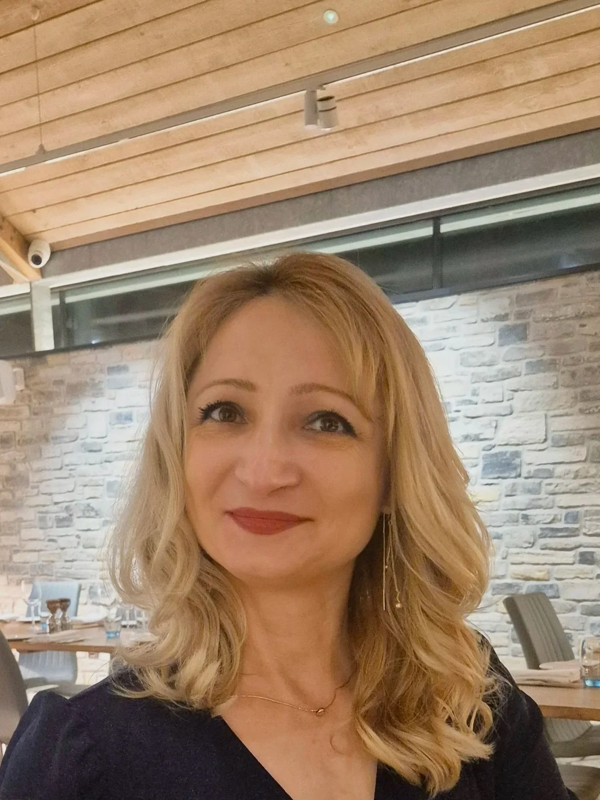 Smiling woman with shoulder length blond hair and wearing a grey jumper