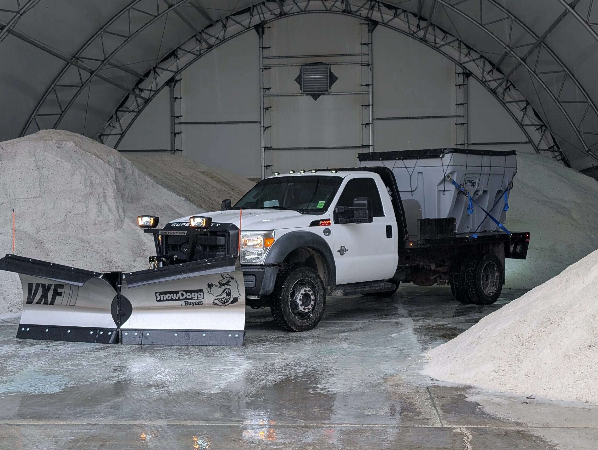 SnowDogg VXF95II V snow plow with LED headlights mounted to Ford F450. A Hilltip 3400AM in the bed of the truck.