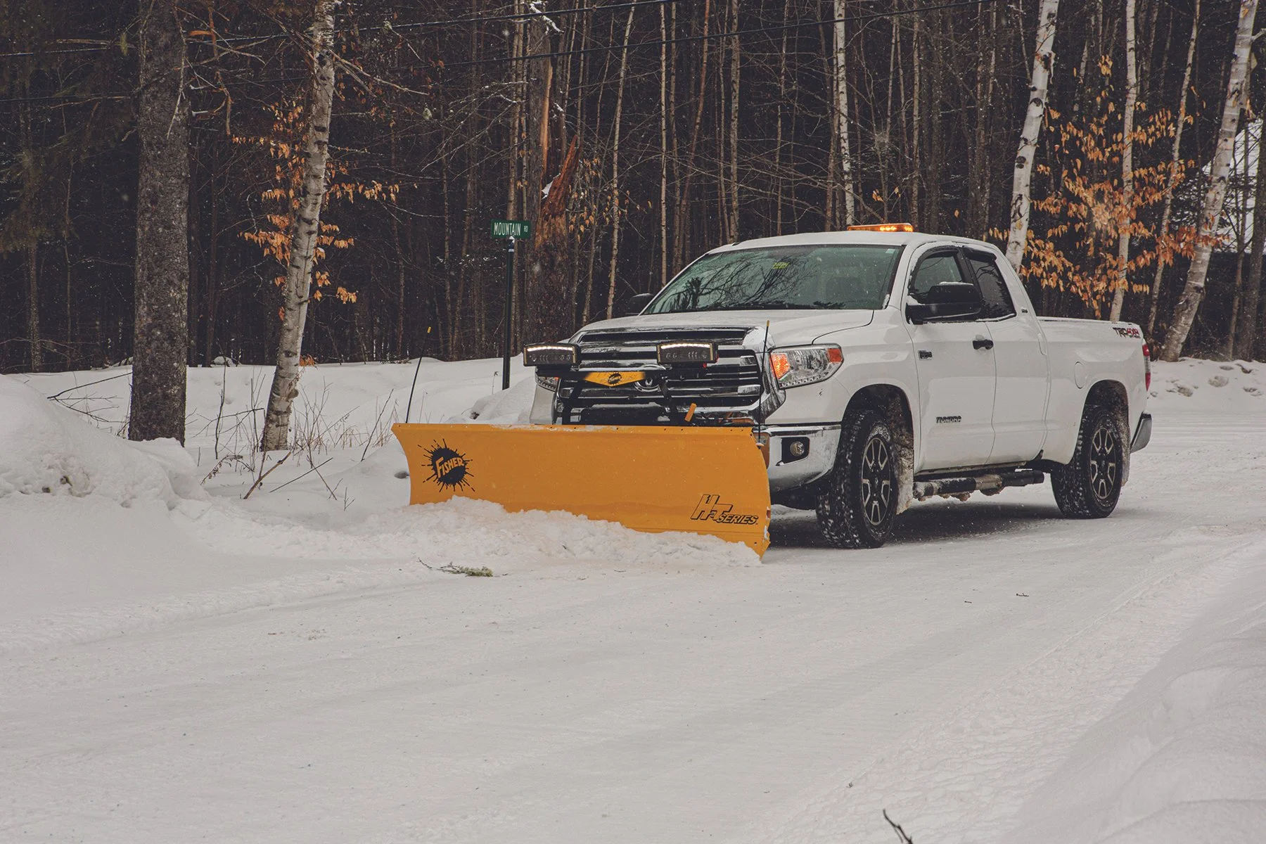 Action shot of a Fisher HT snow plow with LED lights attached to Toyota Tundra