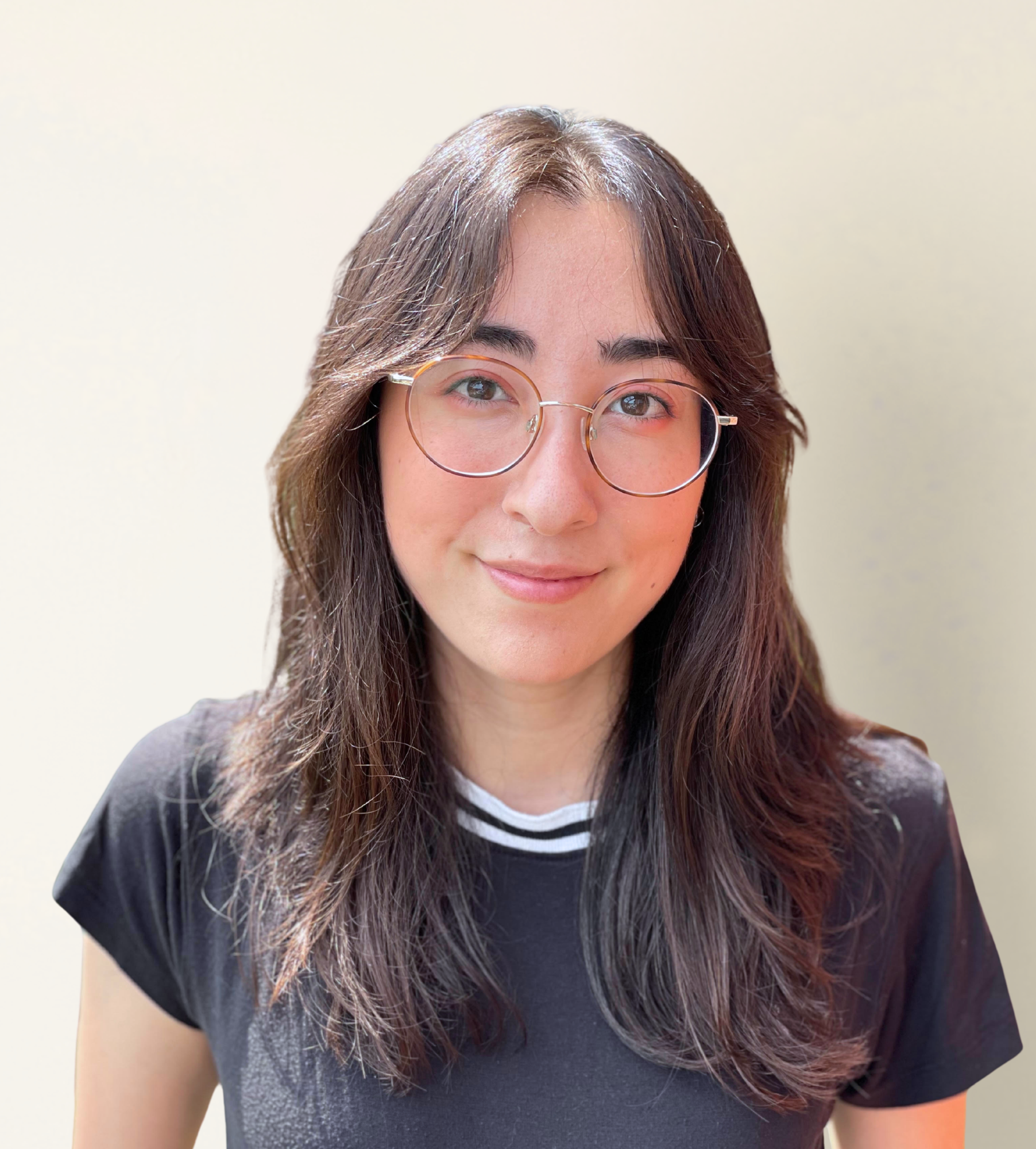 Close-up of a woman's face showing her eyes, glasses, and hair, with a plain light background.