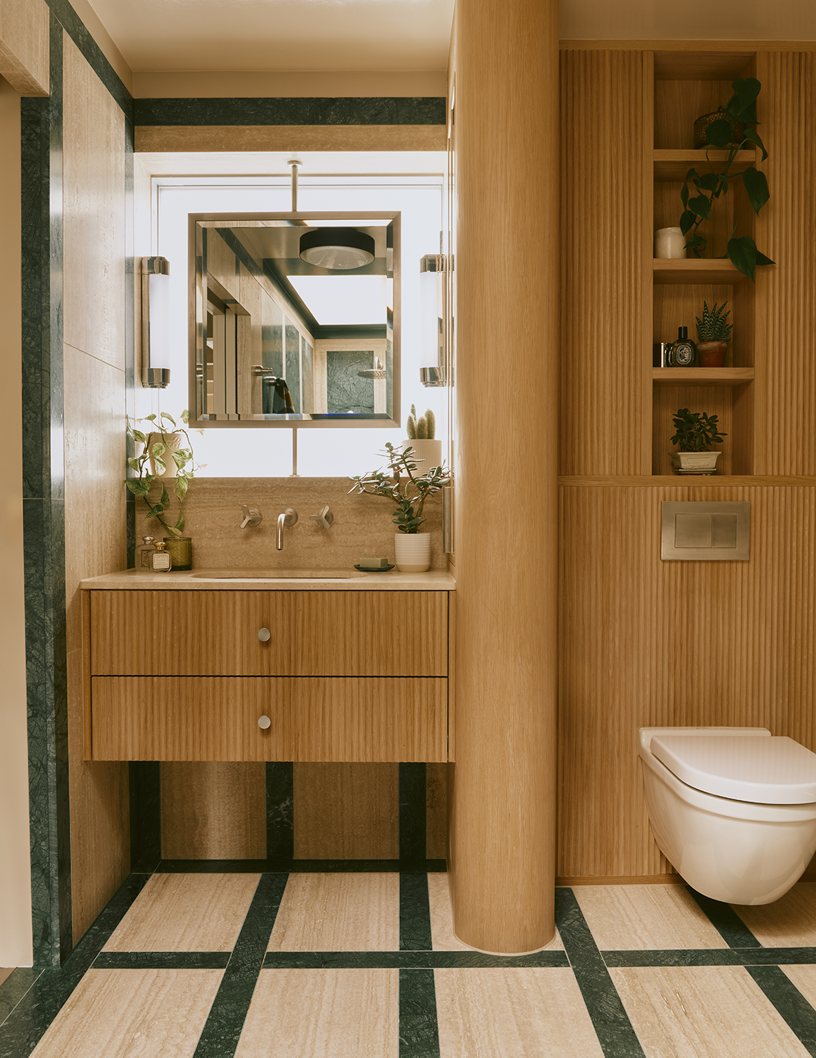 Modern bathroom with wooden vanity, plants, mirror, toilet, and shelving.