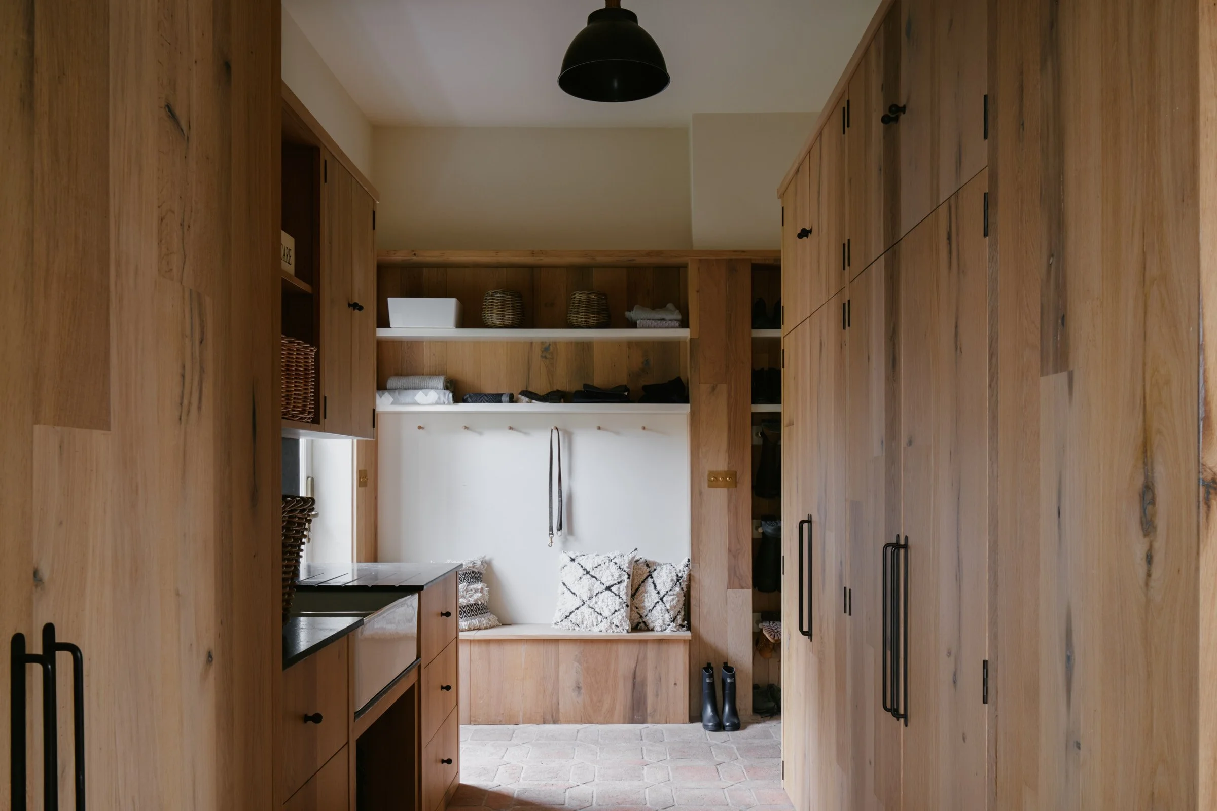 Wooden cabin hallway with built-in shelves, pillows, and black boots