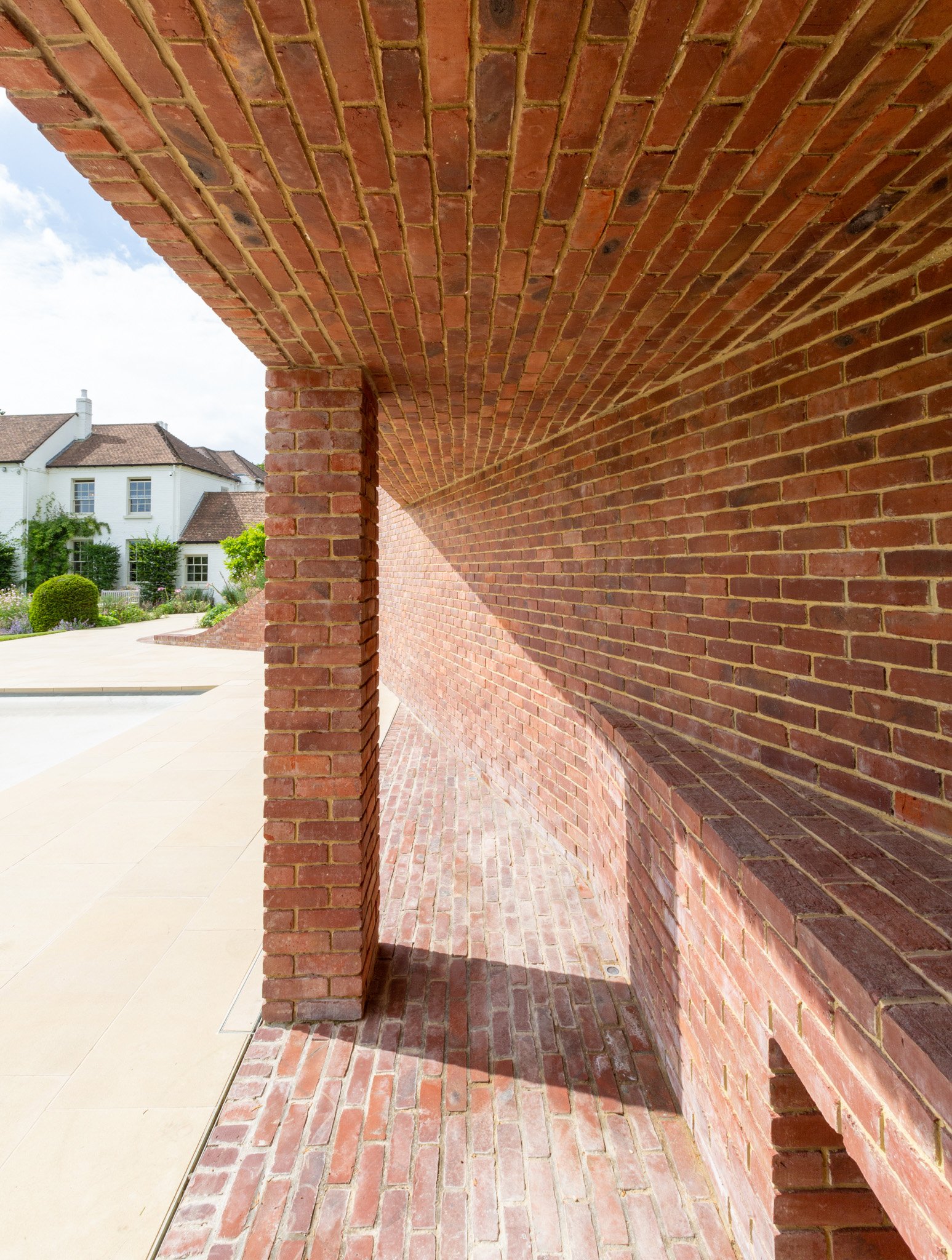 Curved brick wall and ceiling with red bricks, part of an outdoor architectural structure.