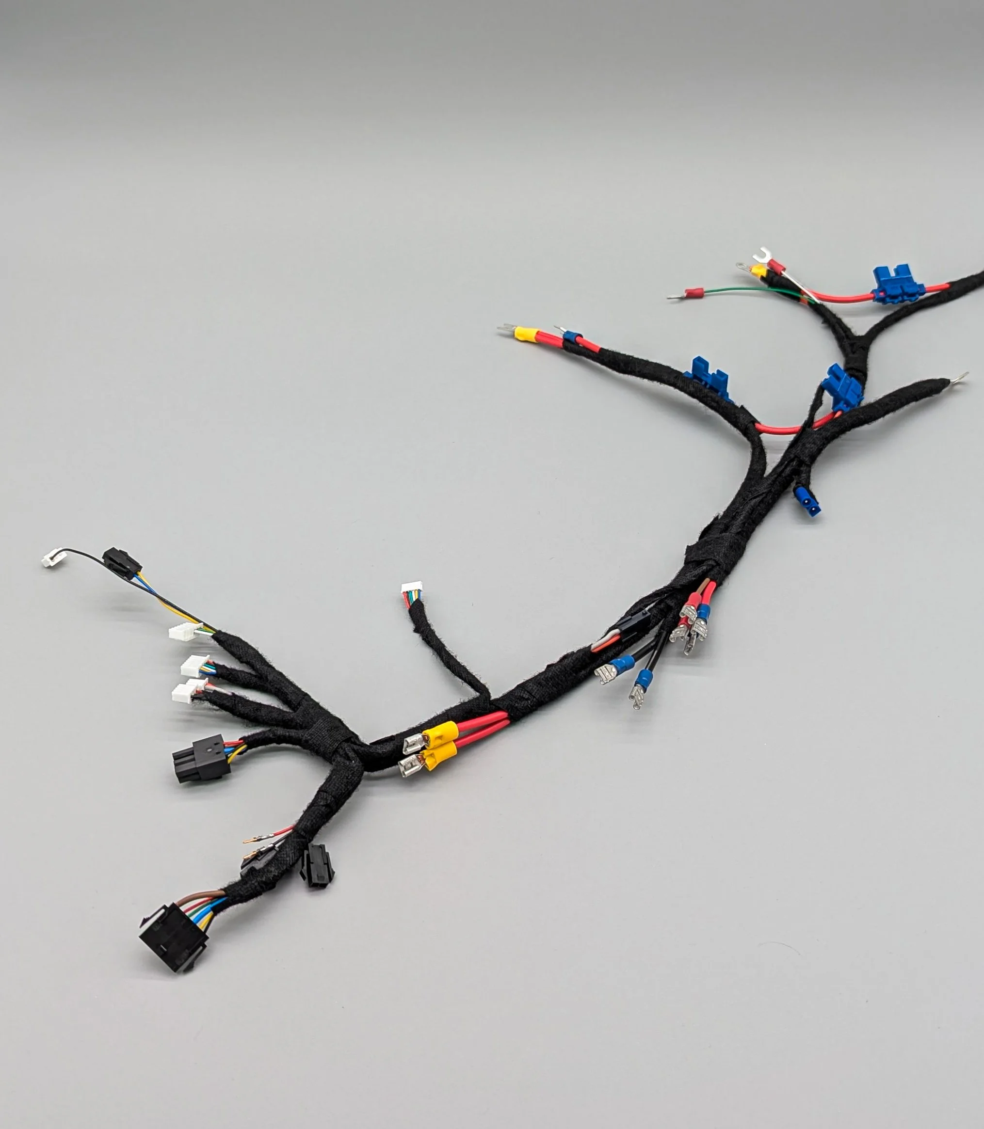 Automotive wiring harness with multiple colored connectors and wires on a grey background. VTS Online
