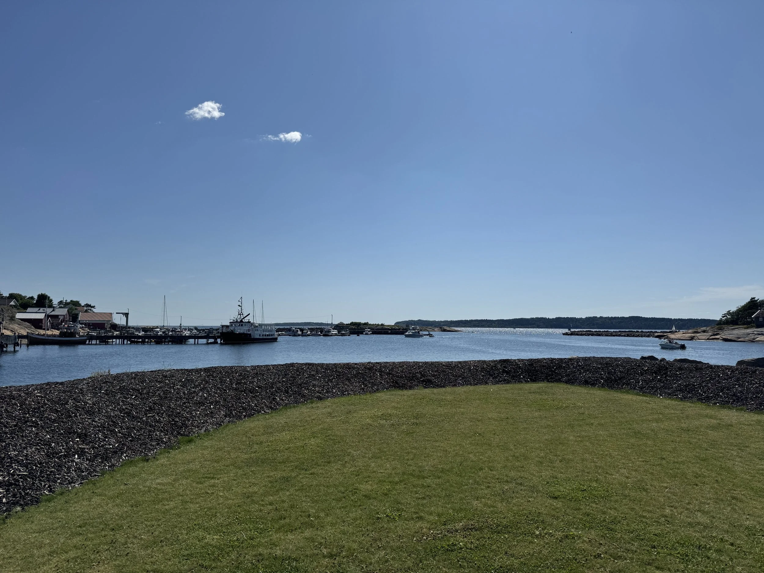 Utsikt over en havn med båter og en klar blå himmel.