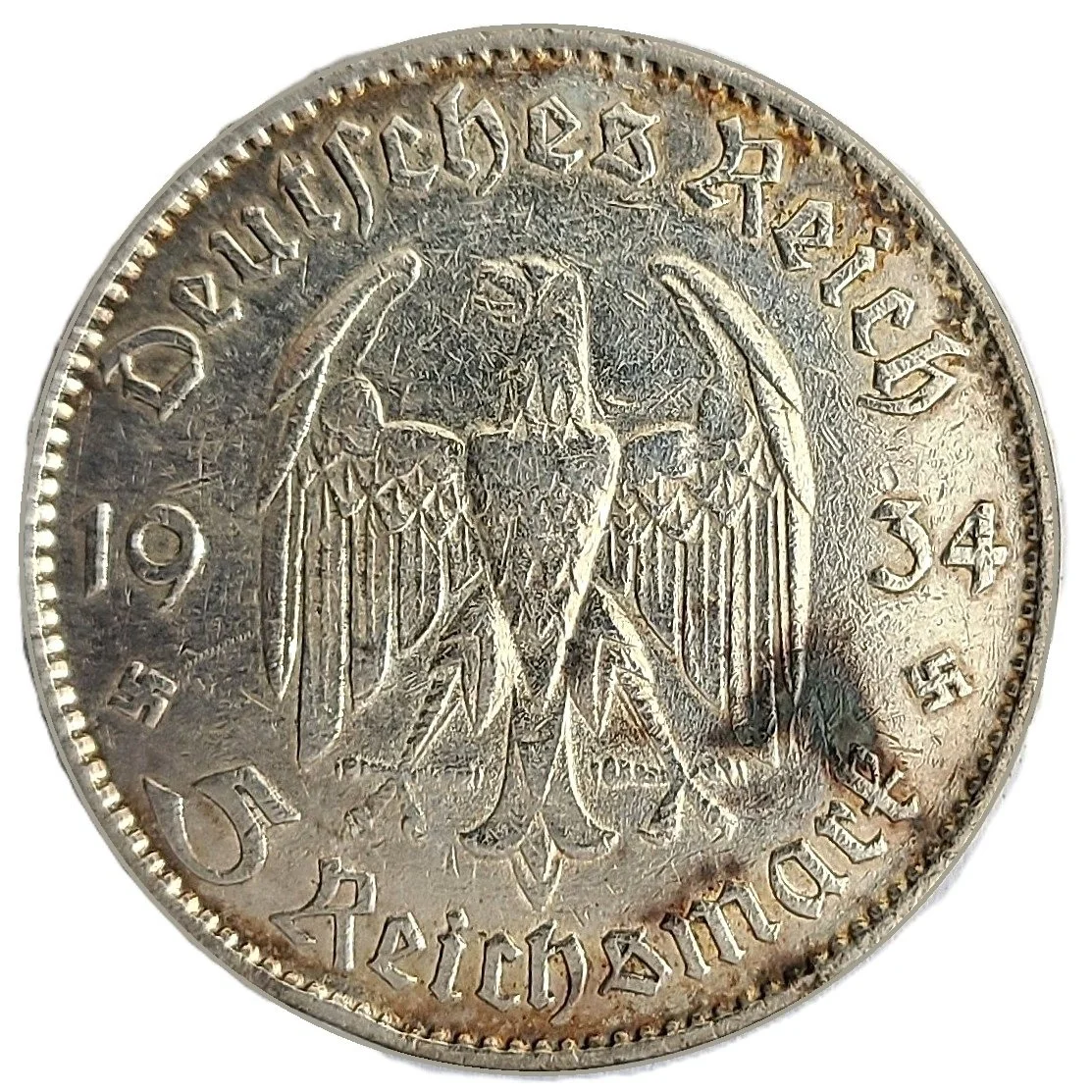 A 1934 German coin featuring an eagle with a swastika, surrounded by German text, and the year 1934