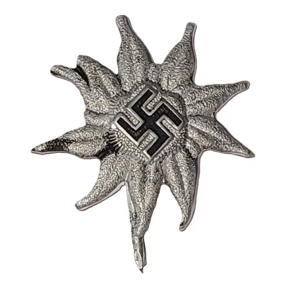 A metallic pin shaped like a starburst with a swastika symbol in the center, indicating association with Nazi imagery.