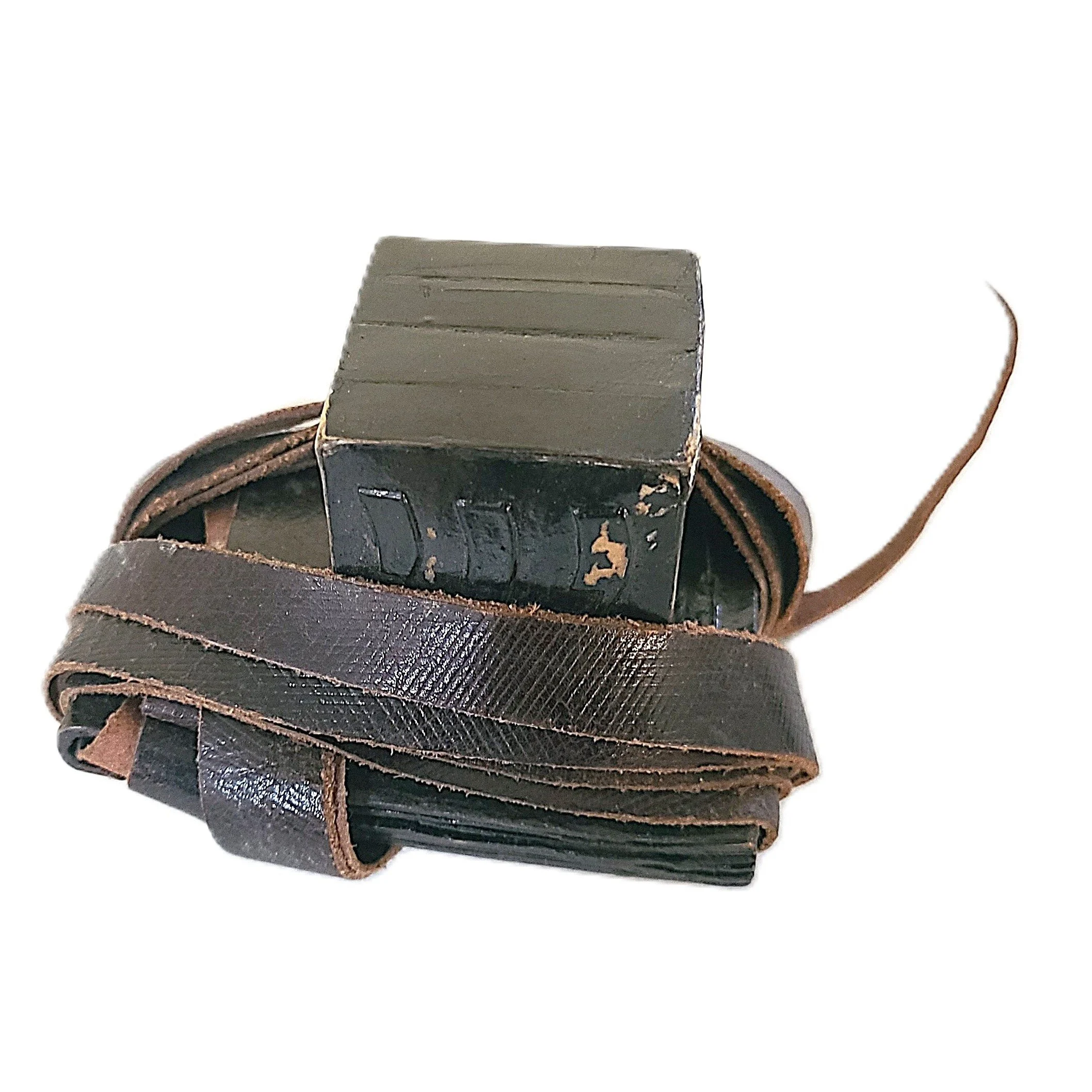 An old, worn black leather strap coiled around and a black leather box