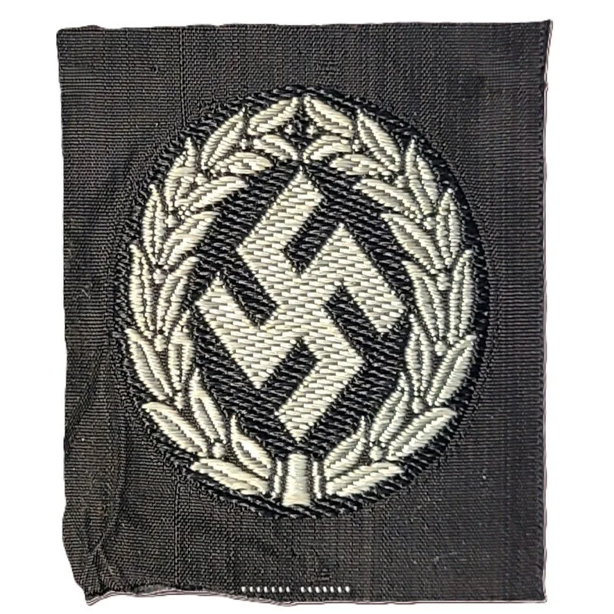 A fabric patch with a swastika symbol enclosed in a laurel wreath design, depicting a Nazi insignia.