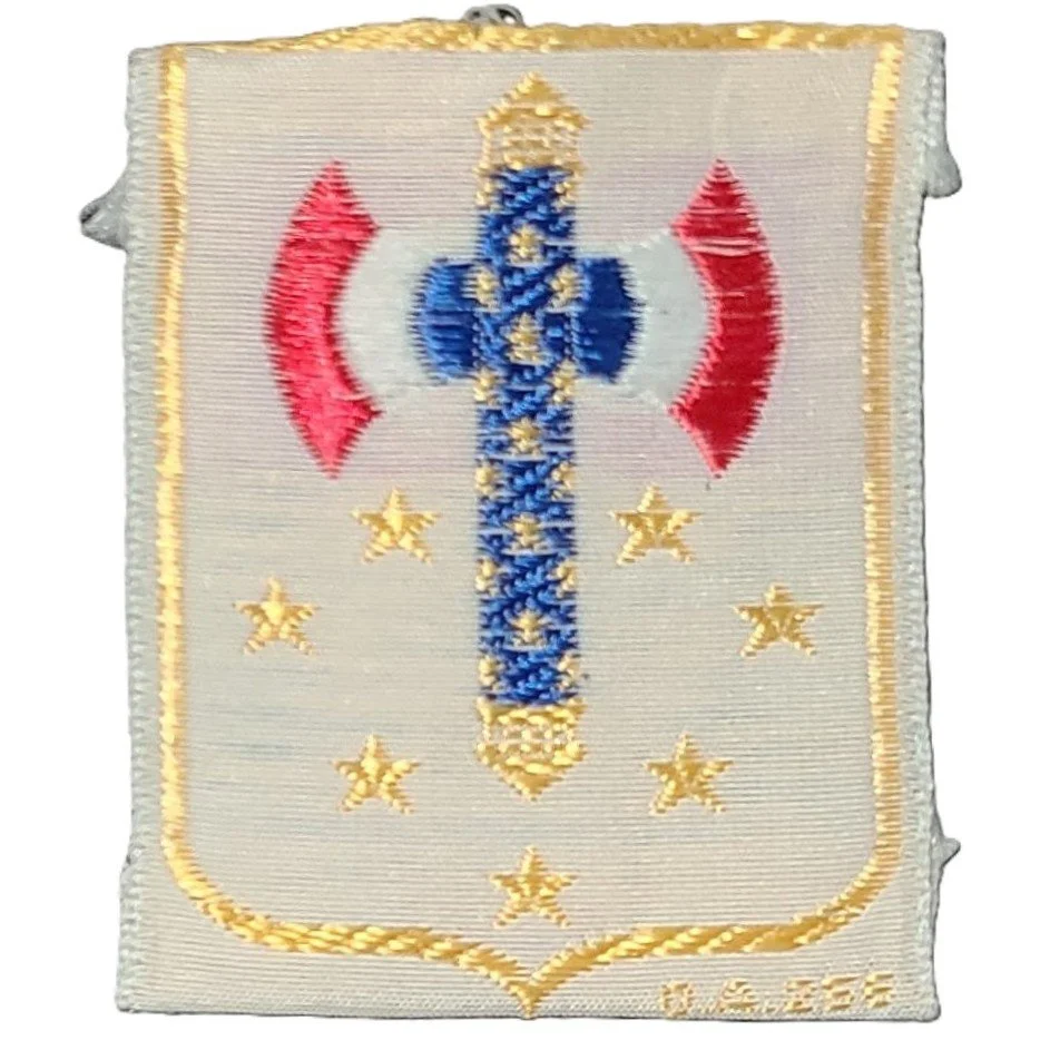 Embroidered military patch featuring a sword in the center, crossed red and white flags, and gold stars on a light background.