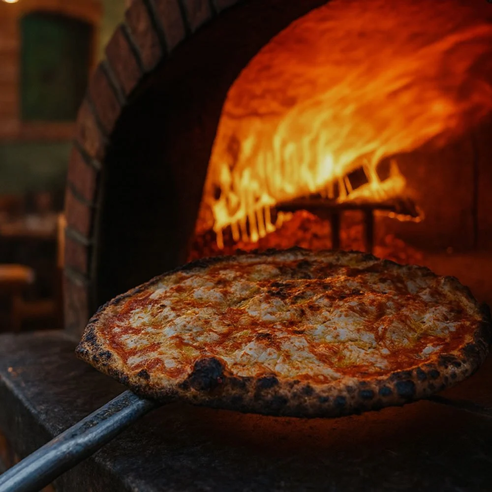 Pizza coming out of a brick oven