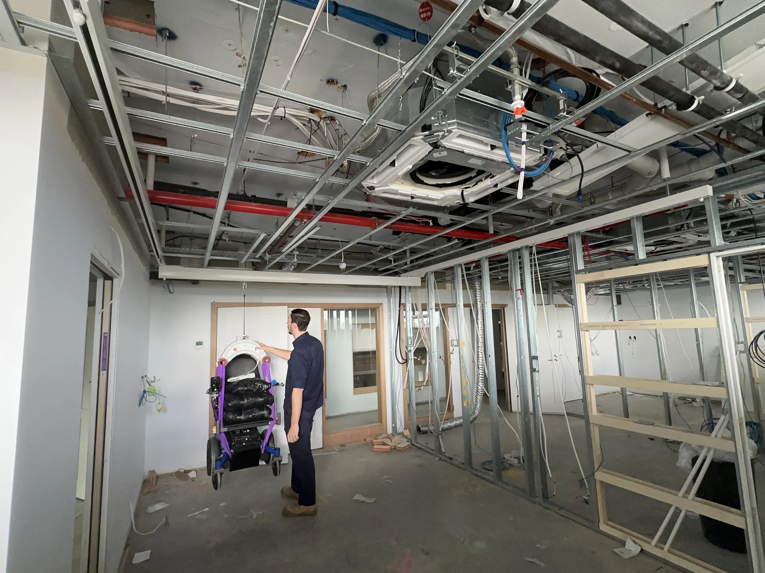 Man in a construction site with exposed metal framework, weight testing a new molift rail system install