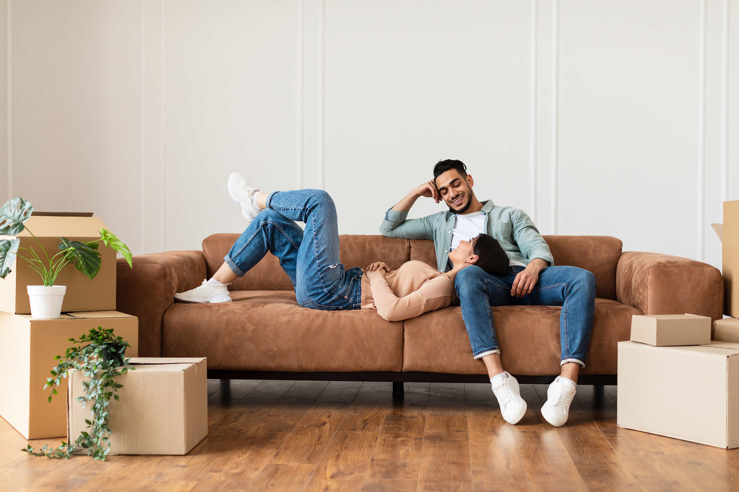 Family relaxing on couch in new home with cardboard boxes