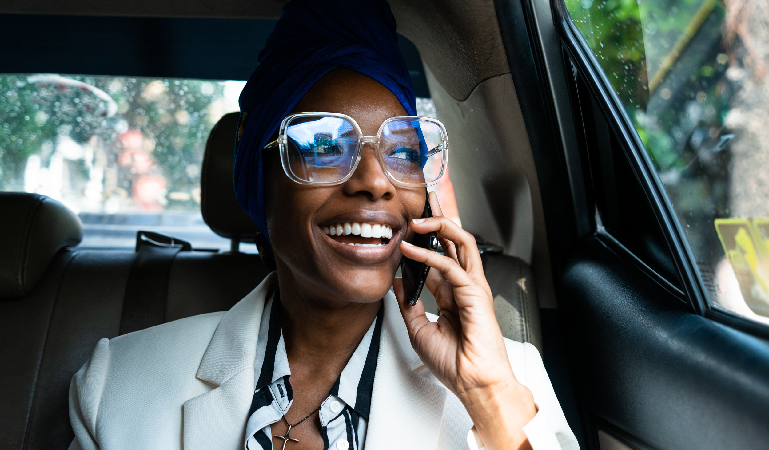 business women in the back of a car speaking on the phone and smiling